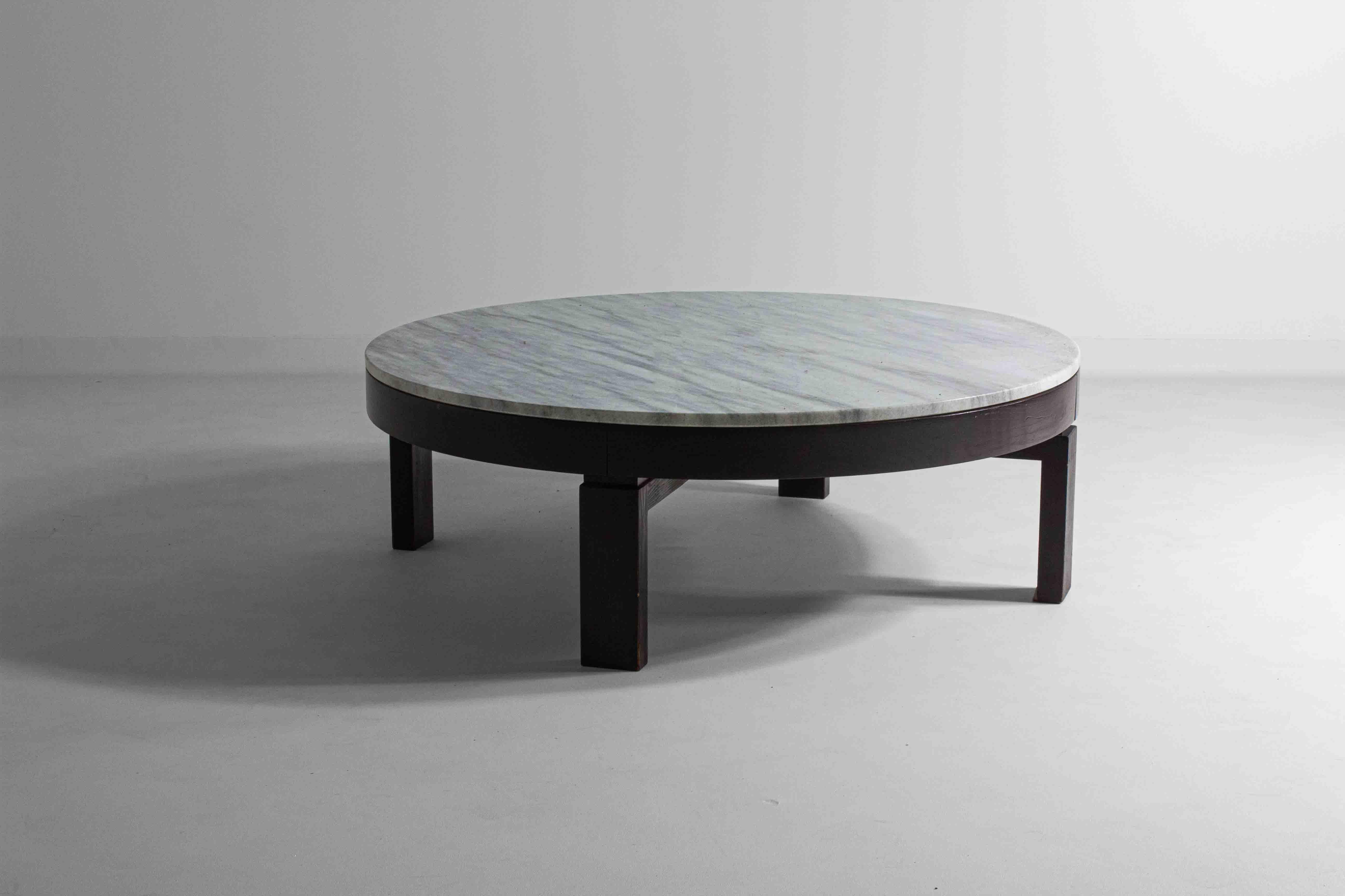 Diese prächtige runde Tischplatte wird von einem robusten dunklen Holzrahmen getragen, dessen tiefe Töne einen prächtigen Kontrast zum weißen Marmor bilden und ein Gefühl von klassischer Grandeur hervorrufen, das ein Synonym für das Design der