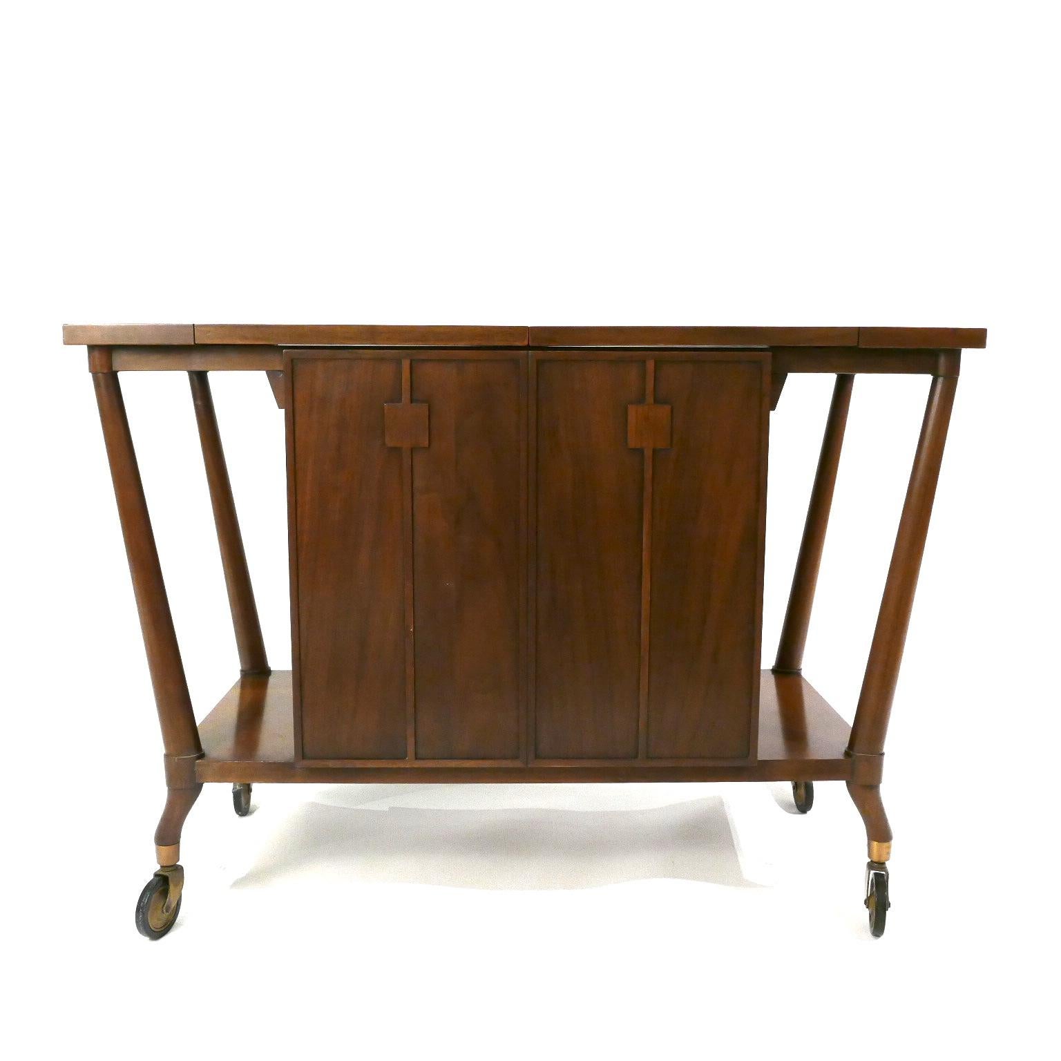 Amazing two-sided bar cart designed for The Forwards Trend Line of Johnson furniture company / Johnson Handley. Sturdy free rolling brass wheels. One side stores drink ingredients with a generous drawer for bar tools. This cabinet also has a lock