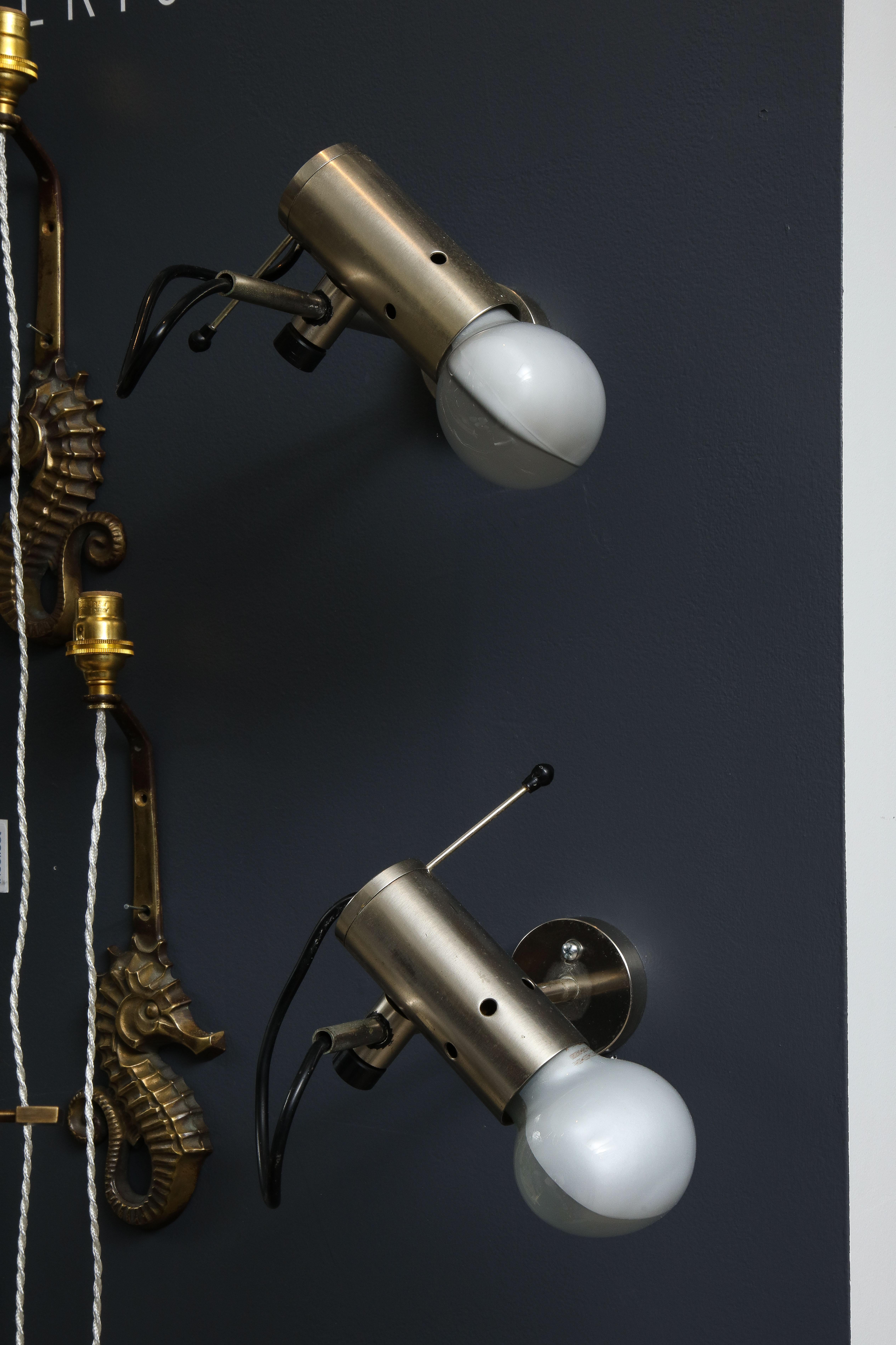 Sleek minimalist pair of nickel-plated bronze wall sconces or bedside lights, by Tito Agnoli for Oluce, 1960s. The shade rotates 360°. European wiring. 