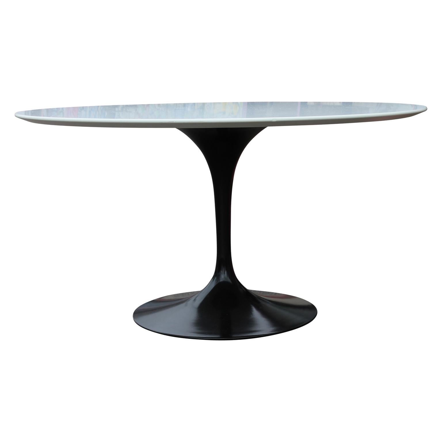 White toped Knoll tulip dining table with a sleek black aluminum base designed by Eero Saarinen. The table is in great condition and has a diameter of 54 inches.