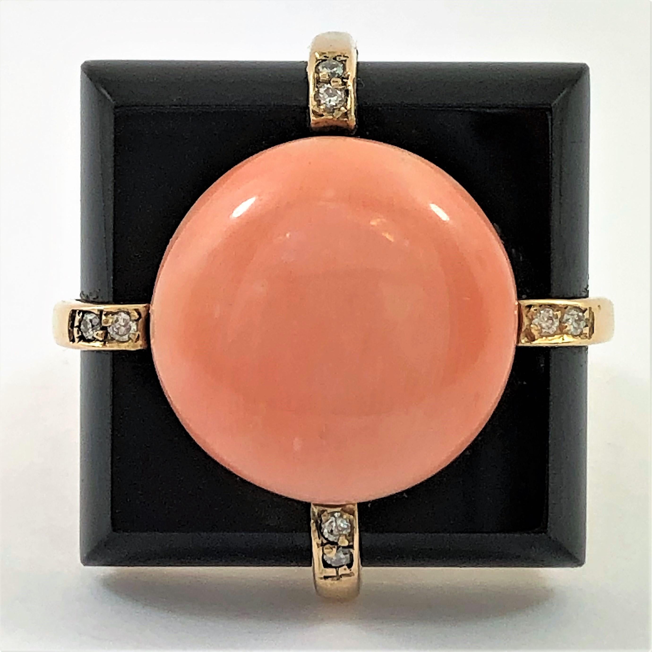 This sleek 18K Yellow Gold ring is set with one round (11/16 inch diameter) Cabochon Angel Skin Coral button on top of a 1 inch square onyx platform. There are four bands of gold at the north, south, east, and west positions. Each gold band is set