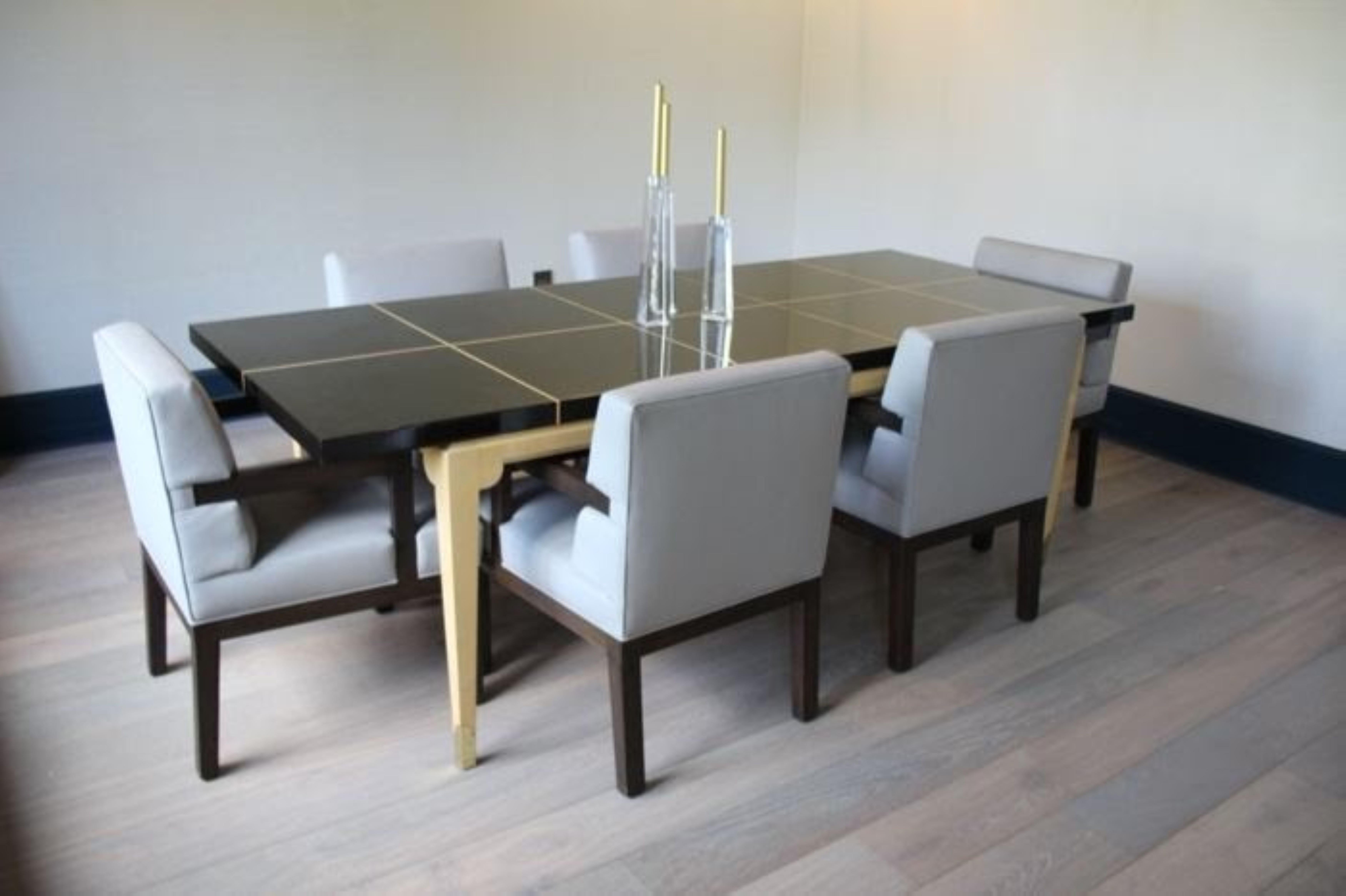 Breathtaking No. 161 dining table by Tommi Parzinger for Parzinger Originals featuring an inlaid dark mahogany lacquered top inlaid with contrasting maple and laquered maple legs terminating in elegant brass sabots. There are two 18” table leaves