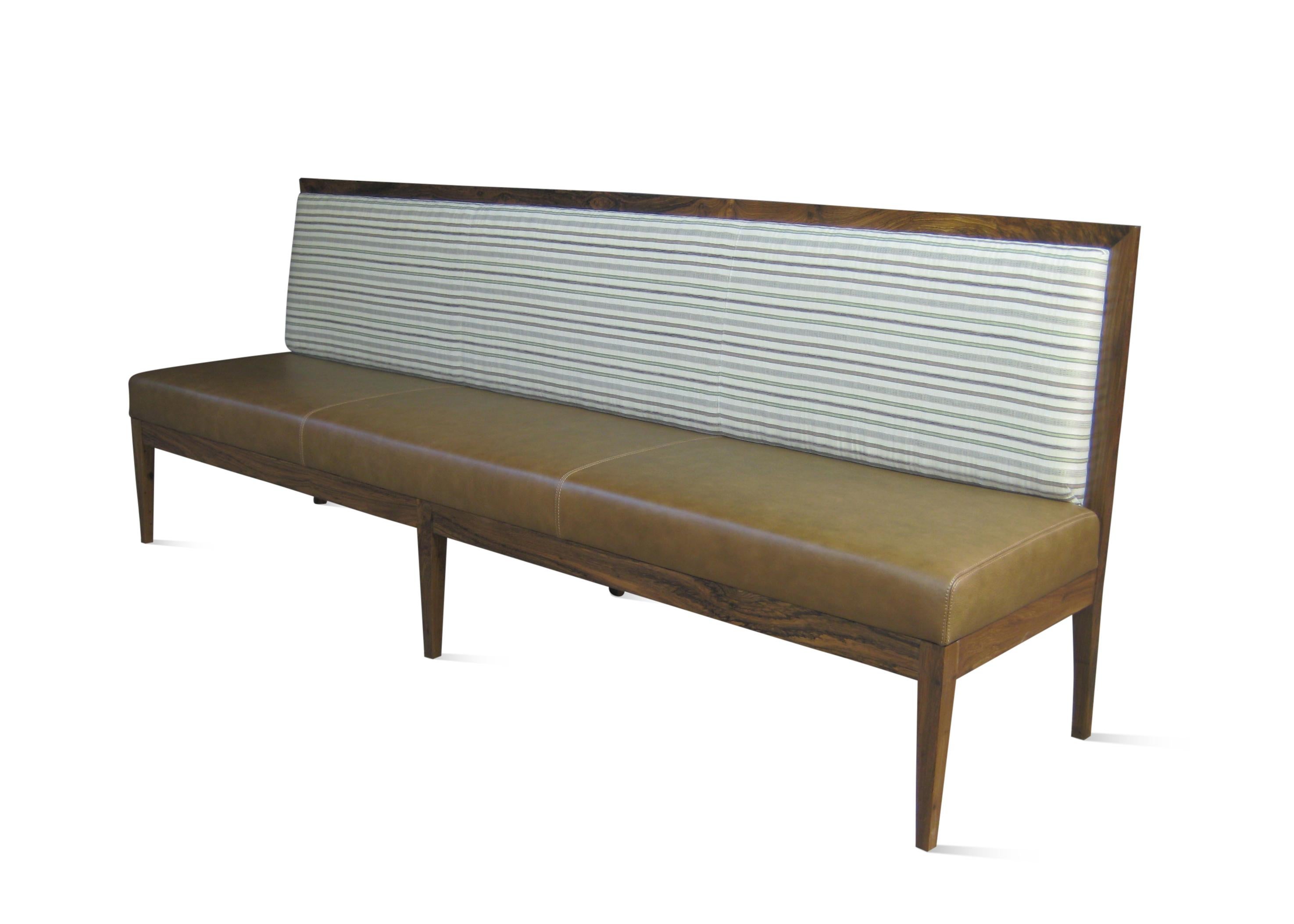 The Novecento Settee features a low, sleek solid wood frame and tight upholstery made to the size and shape you wish. Shown here in an Argentine Rosewood finish with contrasting upholstery, but available in any material or finish and the upholstery