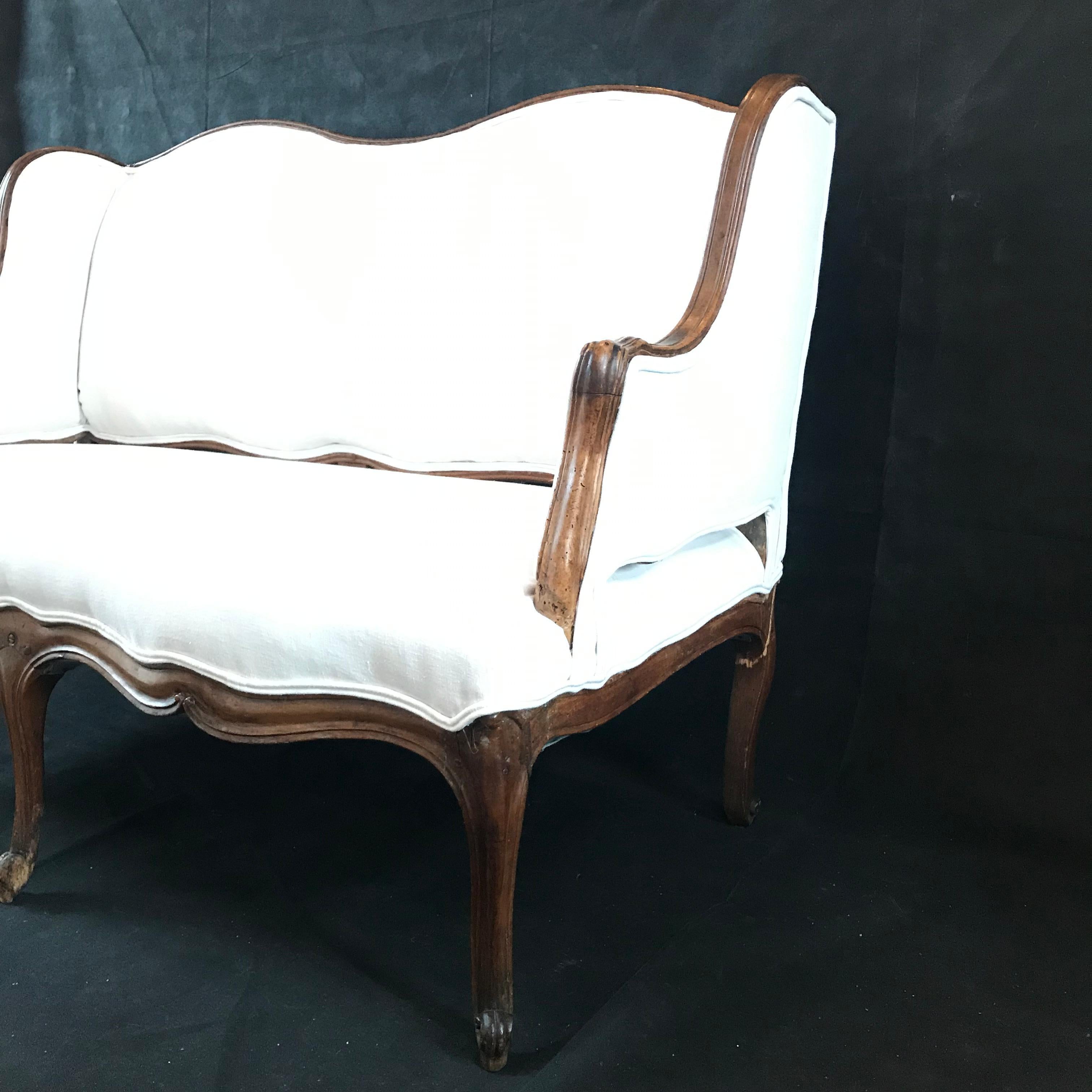 Hand carved walnut loveseat with a sophisticated sleek shape and new white upholstery. Seat height 17.5.
