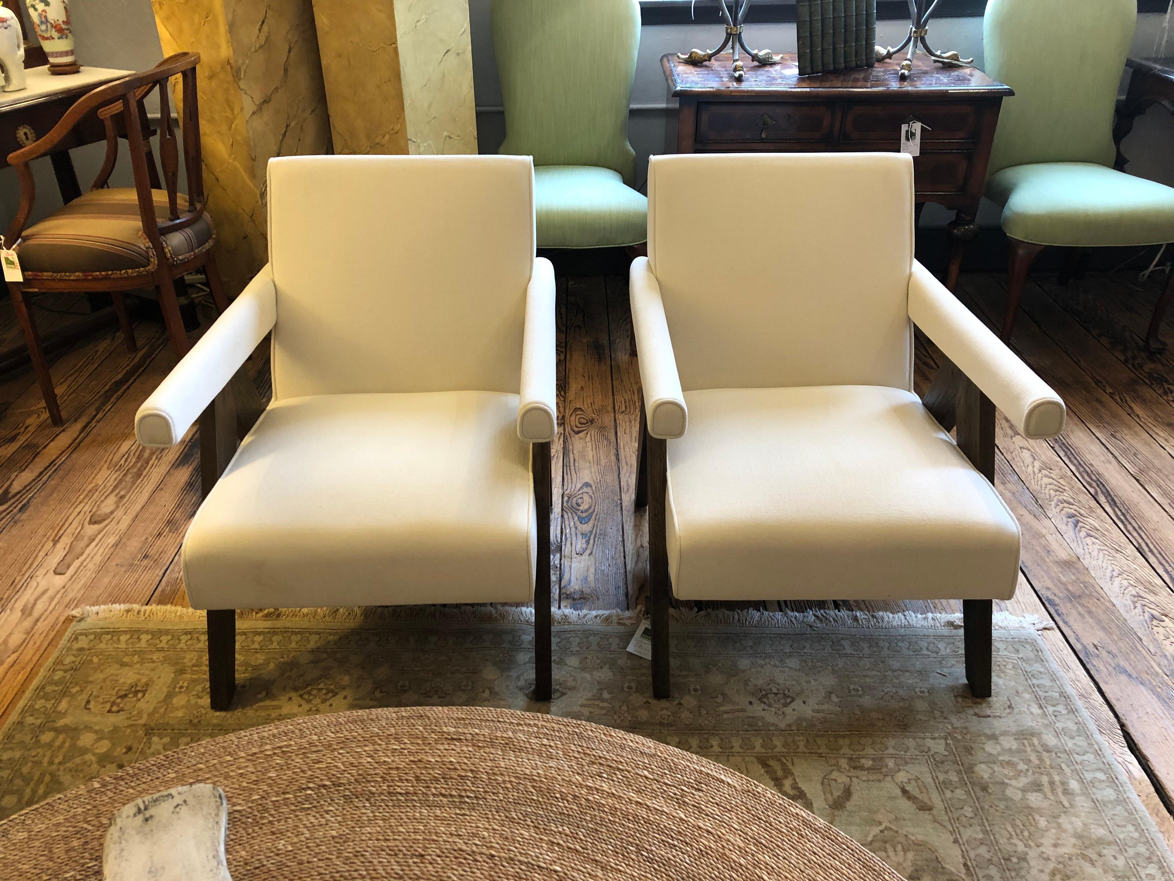 Striking sleek pair of designer club chairs having neutral white upholstery and upside down V walnut legs.  Great style and barely used.