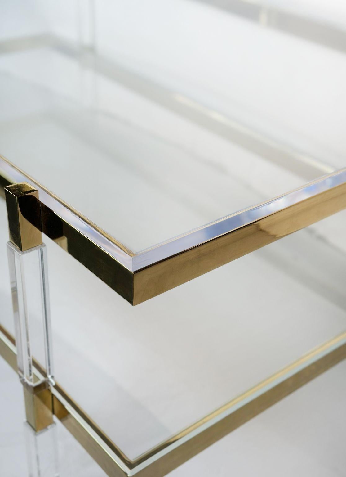 Vintage Two-tier lucite coffee table with brass frame and details by Charles Hollis Jones for his Metric Collection designed in 1960's.
The table's most striking feature is its elegant use of lucite, a material known for its transparency and