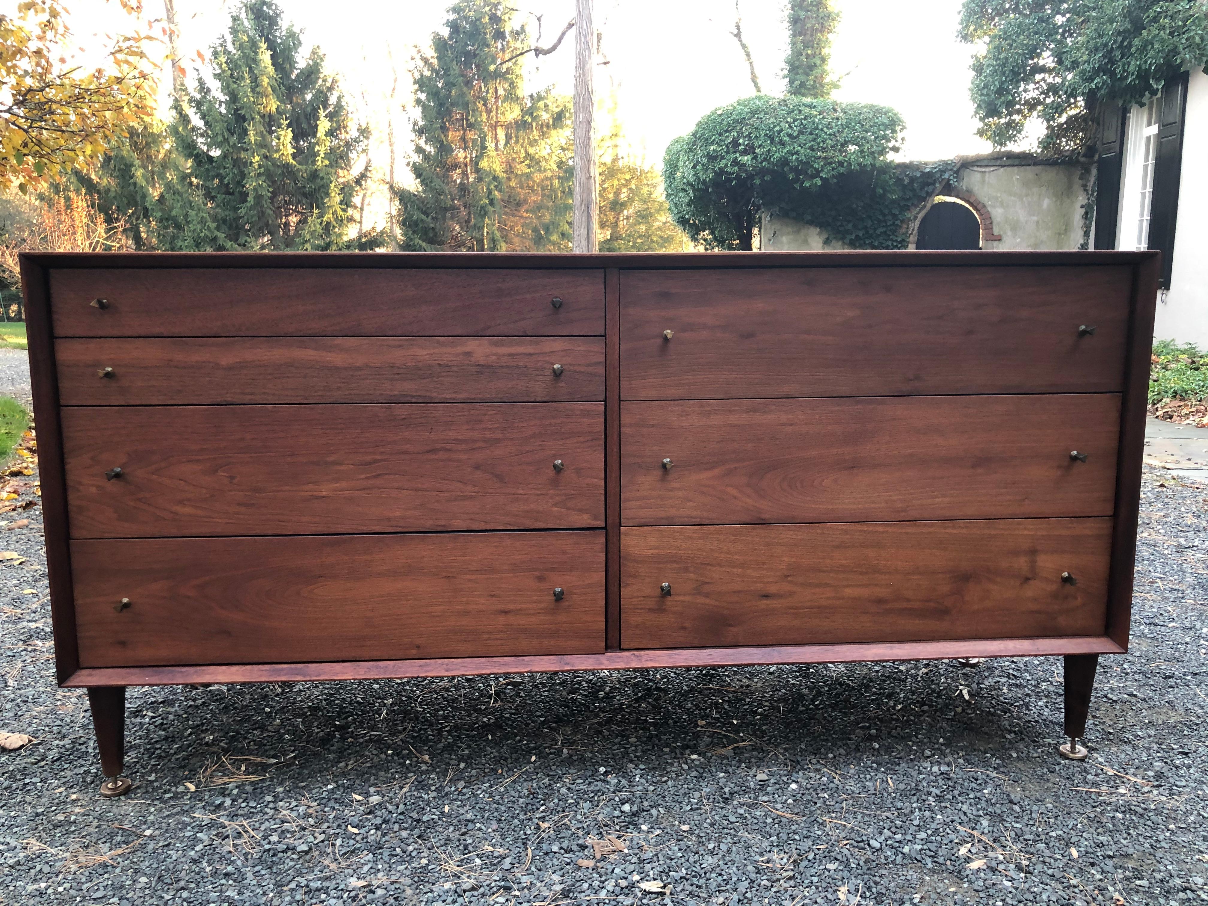 A handsome midcentury credenza dresser by renowned furniture maker Grosfeld House. Made of walnut, the credenza has a beveled frame front. The seven drawers each have metal triangular pulls and the edges of each drawer have a matte black finish. The