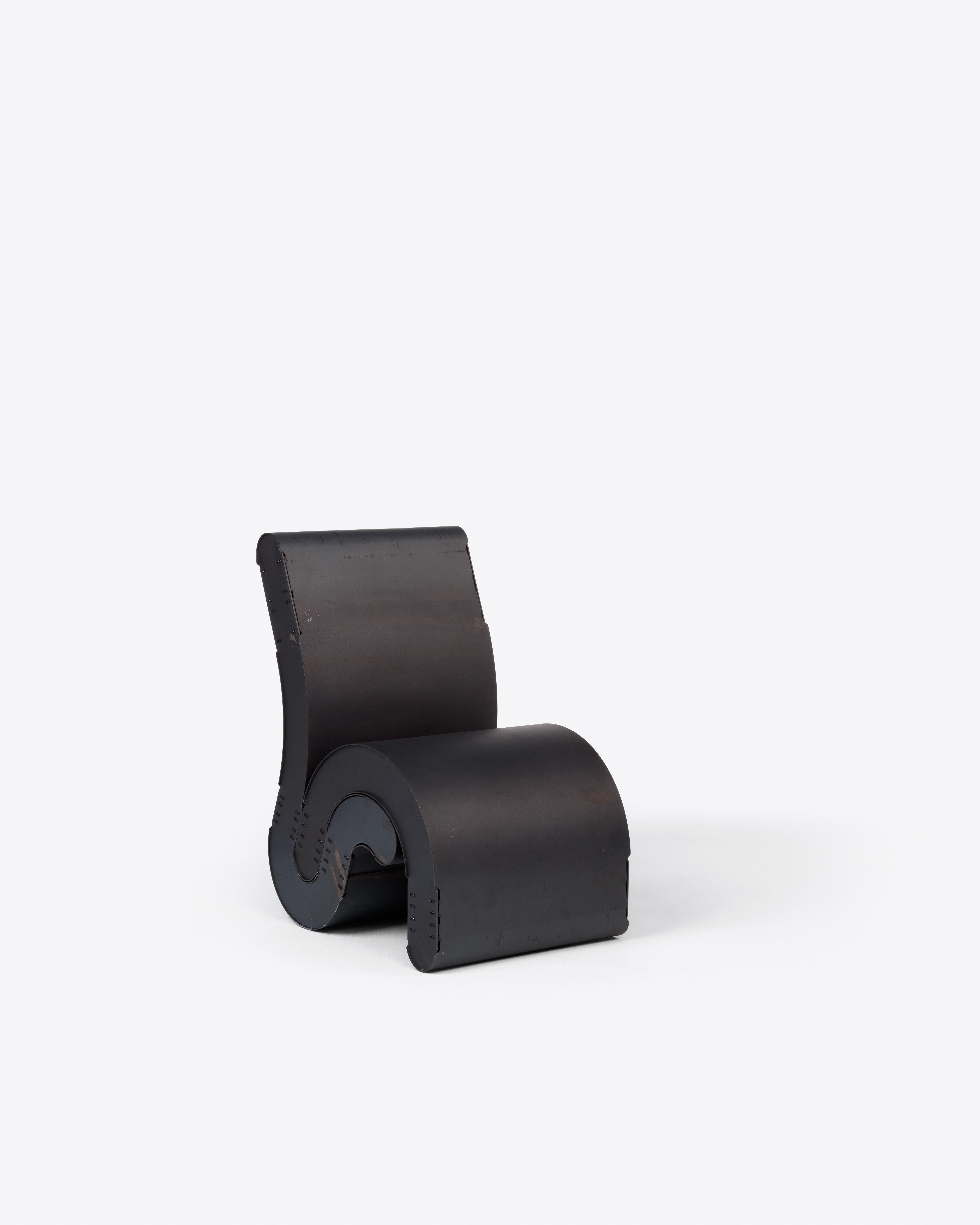 Dieser Loungesessel aus rohem Kohlenstoffstahl ist aus der Serie Sleepers von Simões hervorgegangen. Seine monolithische Form krümmt sich zu einer durchgehenden Schnecke, die Sitz und Stütze in einer einzigen Geste vereint. Die mattschwarze