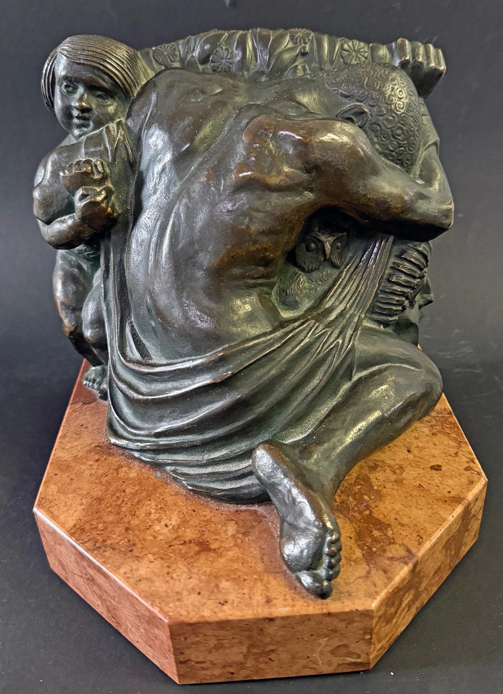 Questo grande e pesante fermalibri in bronzo, splendidamente scolpito, fuso e cesellato, raffigura una figura maschile nuda e addormentata, con il braccio appoggiato su una maschera classica, il corpo rannicchiato intorno a un gufo e il braccio