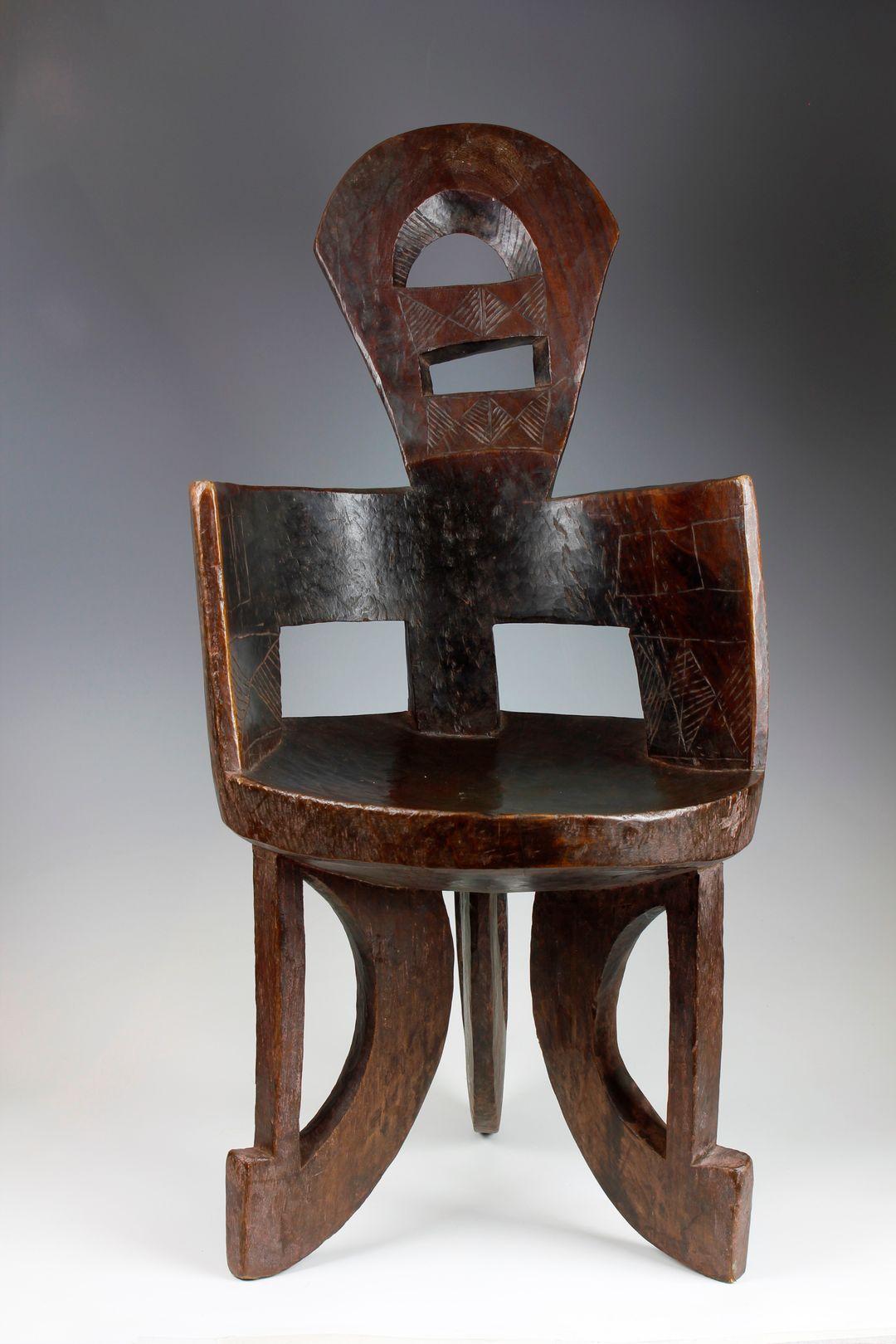 This late nineteenth-century chair, from the Gindabarat in the Oromia region of Ethiopia, has been finely carved from a single piece of dense, heavy wood. The circular, narrow-in-size seat is supported by three legs, which each feature an upright