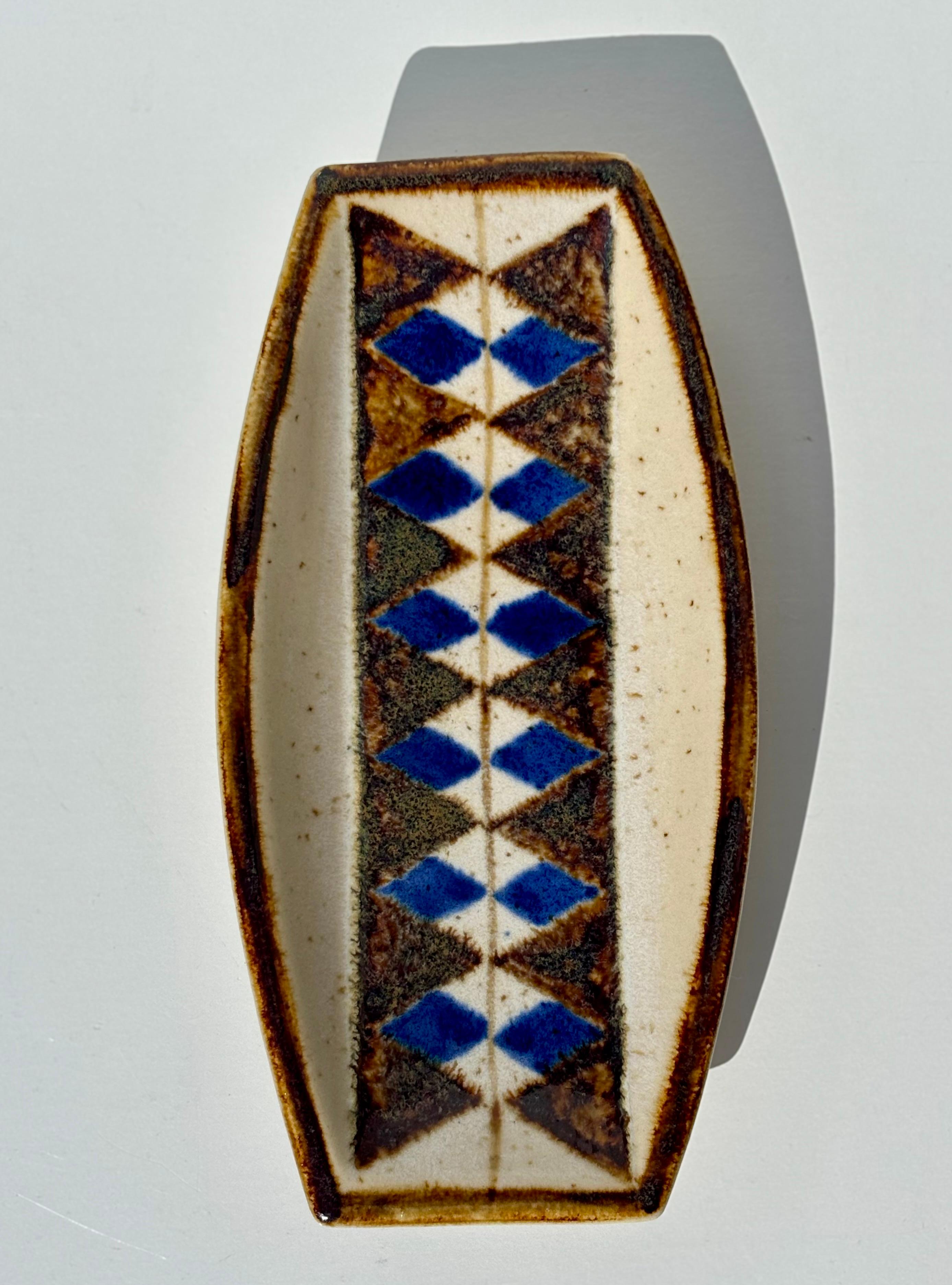 Ciotola vide-poche danese moderna di forma rettangolare morbida di Michael Andersen & Son. Prodotto sull'isola di Bornholm negli anni '60. Smalto color crema con decori geometrici in smalto marrone, blu e ocra. 
Timbro sotto la base. 
Piccola
