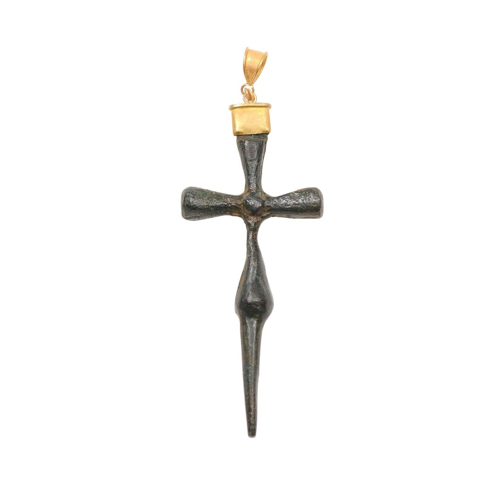 A Byzantine Empire Bronze Cross Pendant with 21 karat gold accents. This slender bronze cross is from the 4th to 6th Centuries AD and was created by lost wax casting. The Byzantine Era ran from the 300s to the fall of Constantinople and the Eastern