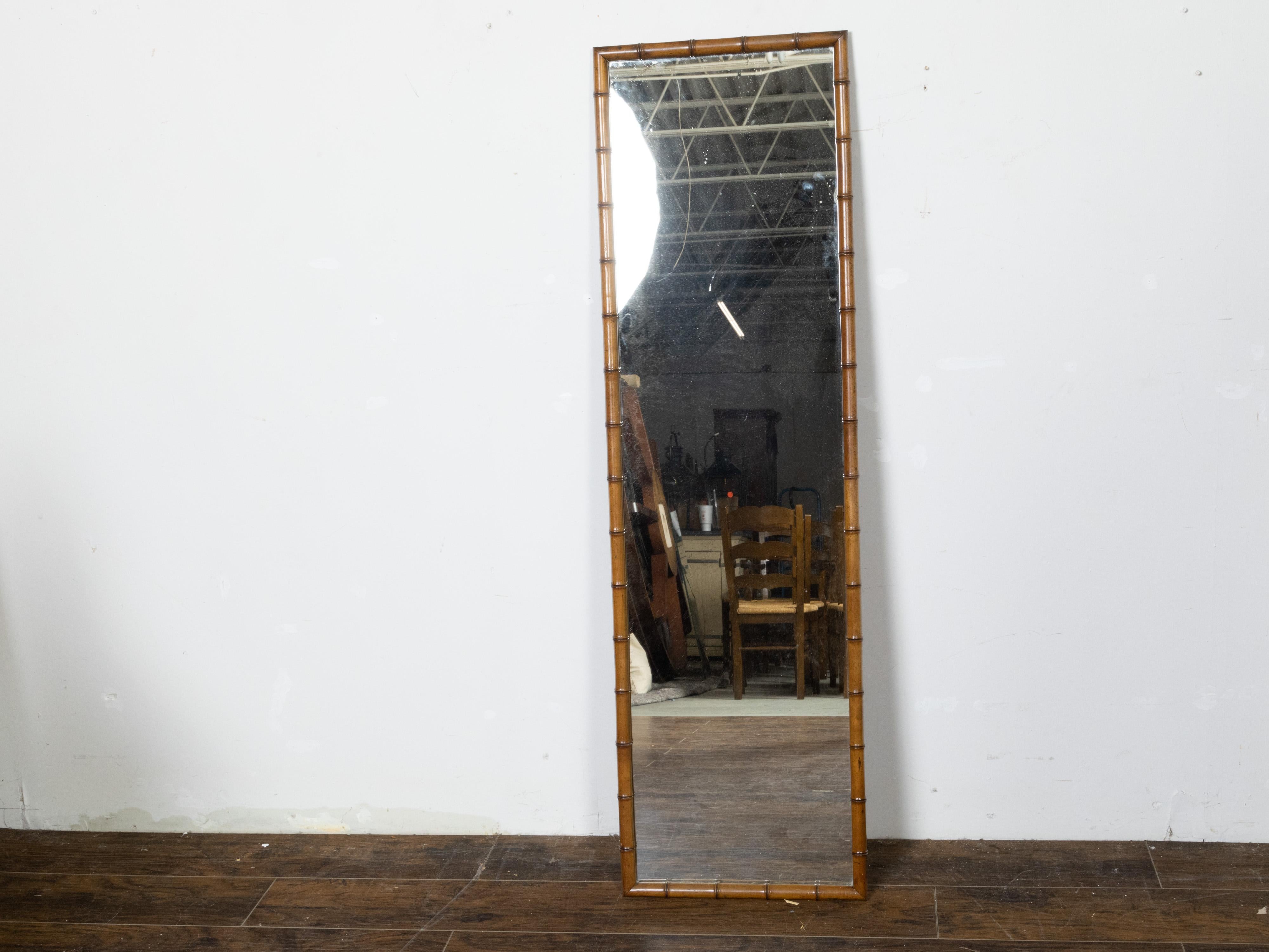 A slender French faux-bamboo mirror from the early 20th century, with simple lines and brown patina. Created in France during the Roaring Twenties in the first quarter of the 20th century, this slender mirror features a linear silhouette perfectly