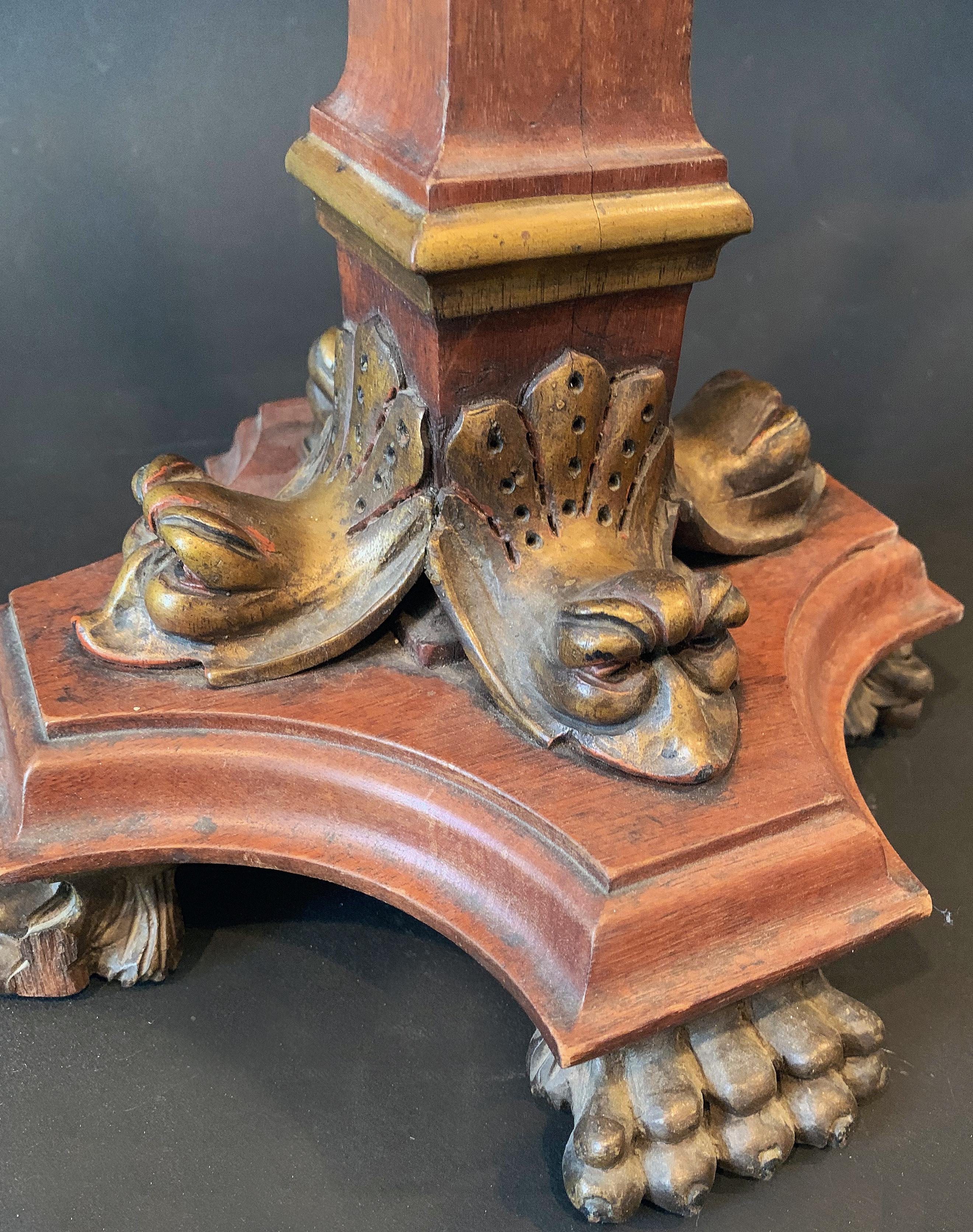 Beautifully carved and finished, this Renaissance Revival lamp base features hairy paw feet, gilded dauphins in the 18th century French manner, fruited garlands midway up the lamp shaft, and a torch at the top, all executed in a warm mahogany.