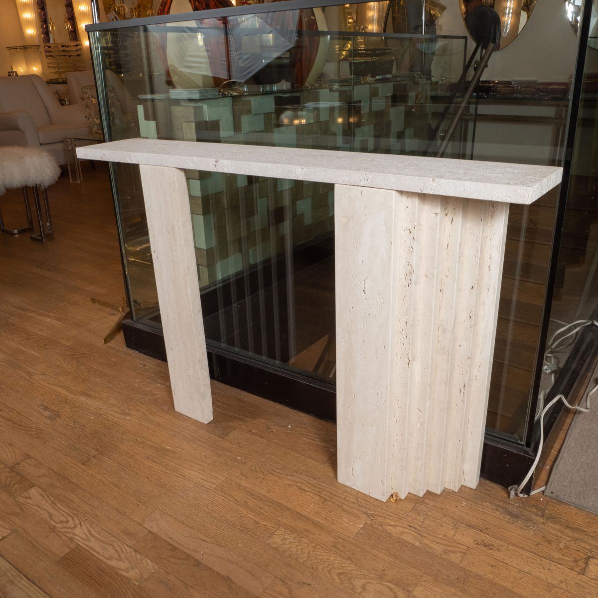 Slender travertine console with stepped design.