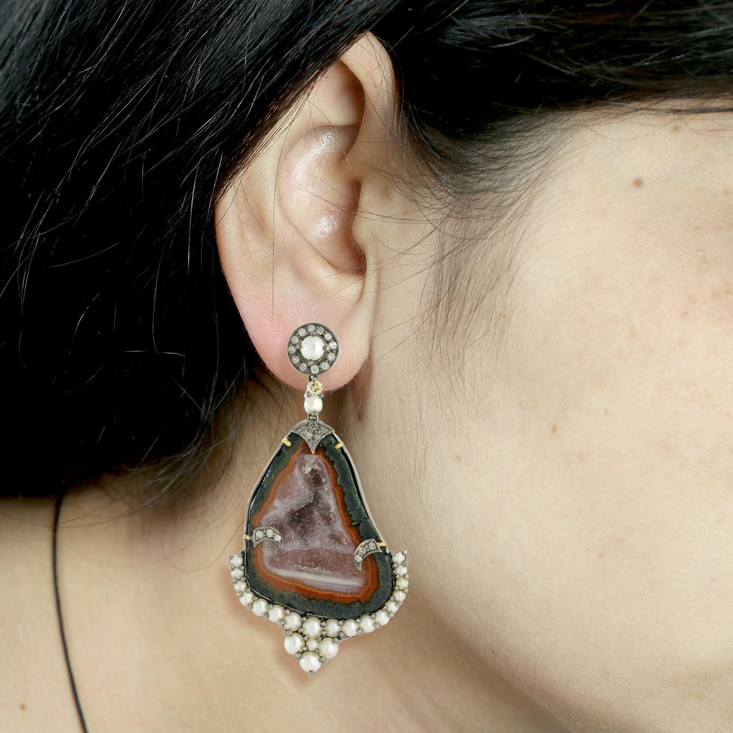The geode is a type of rock that forms inside a hollow cavity in a rock or sedimentary layer. When the geode is cut open, it reveals a beautiful, crystal-like interior. The pearl and diamonds add a touch of elegance and sparkle to the earring. The