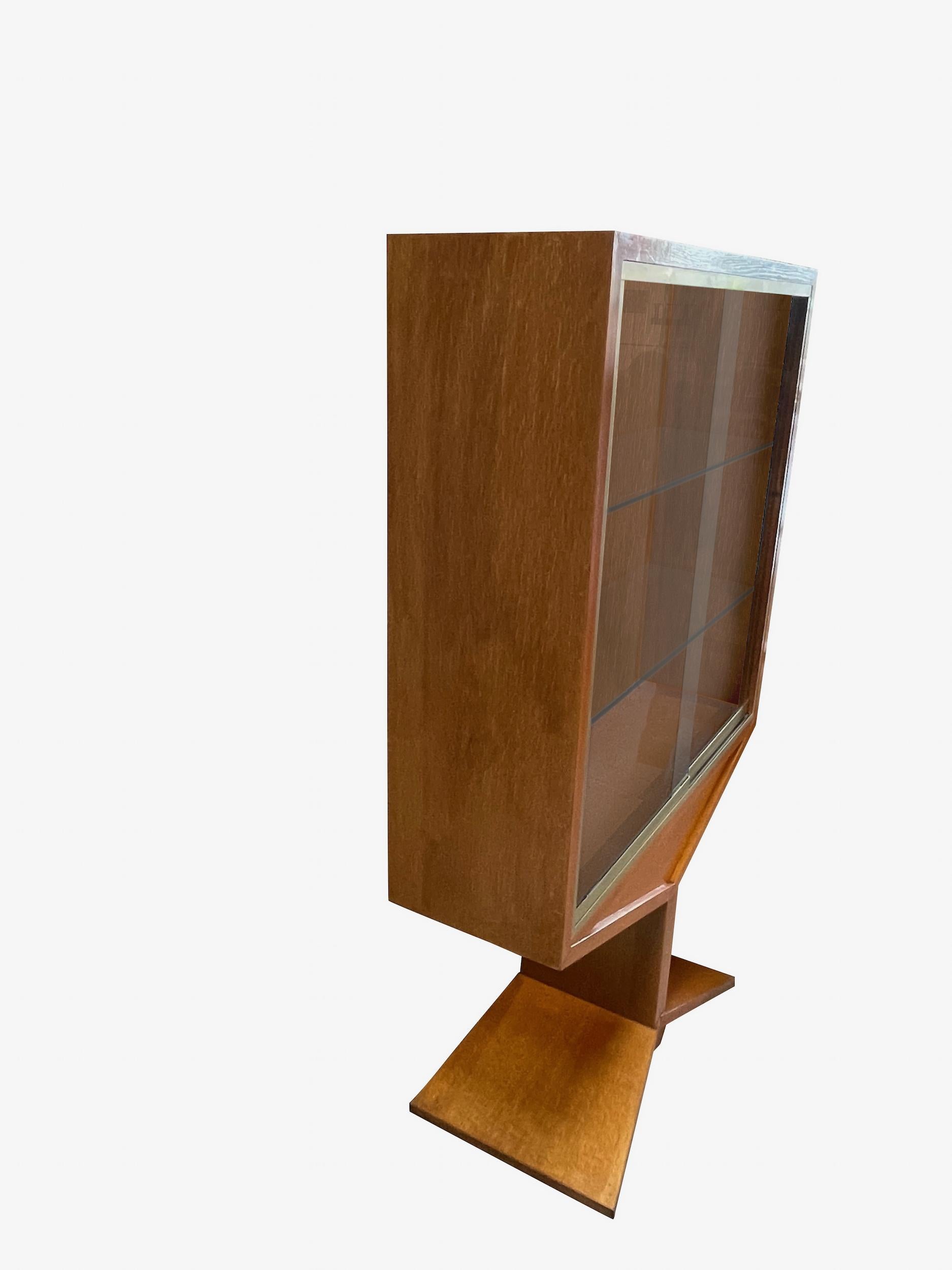 1950's French two door sliding glass front cabinet.
Two interior shelves.
Oak with brass trim detail.
Cabinet sits on decorative pyramid shape base.
