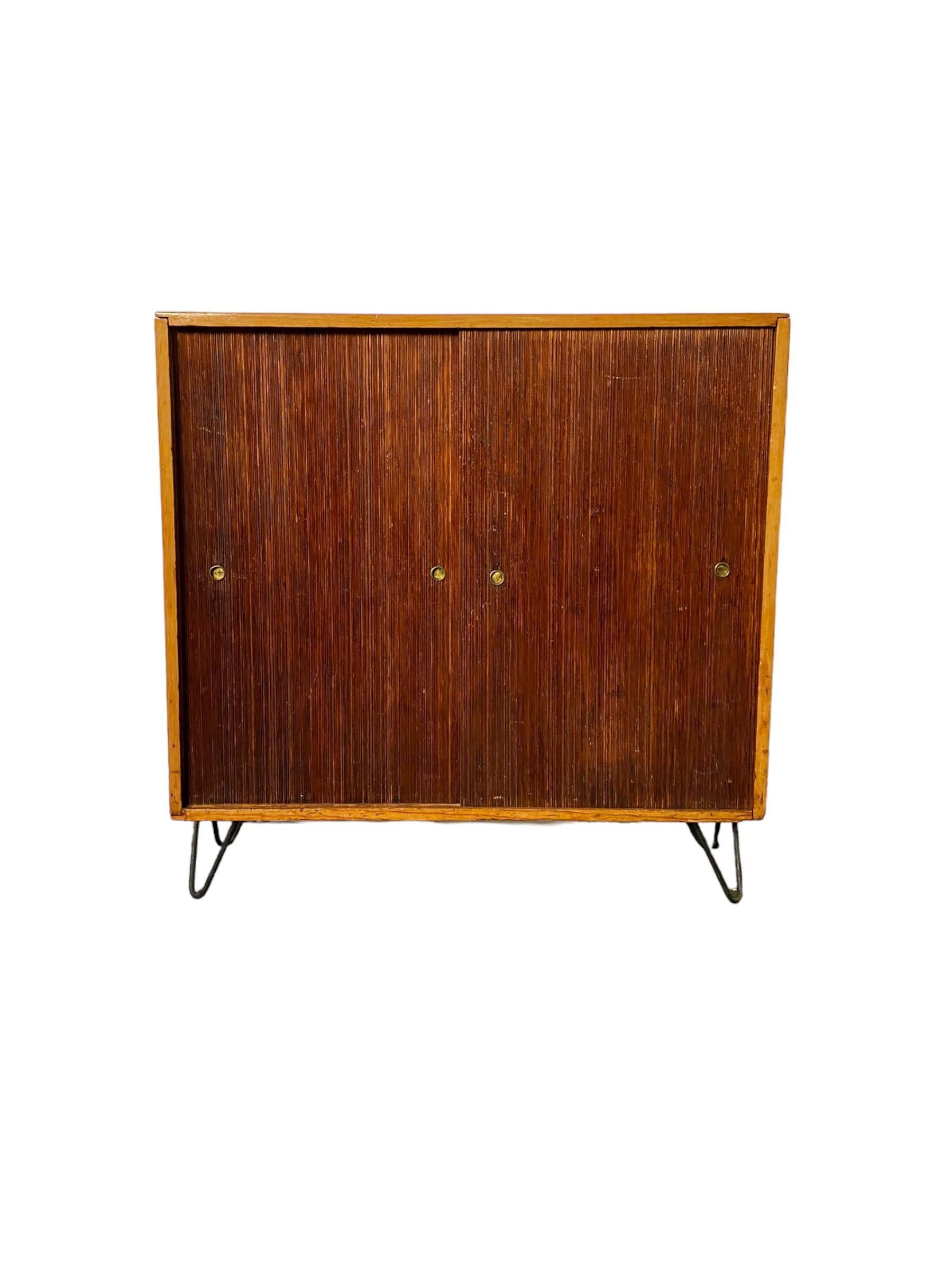 Sliding door two door cabinet from the late 1950s with two shelves. Tamboor doors in good vintage condition. Doors slide with ease. Cast iron hairpin legs. Two tone wood frame and doors. Great as a sideboard for easy and handsome storage. Small