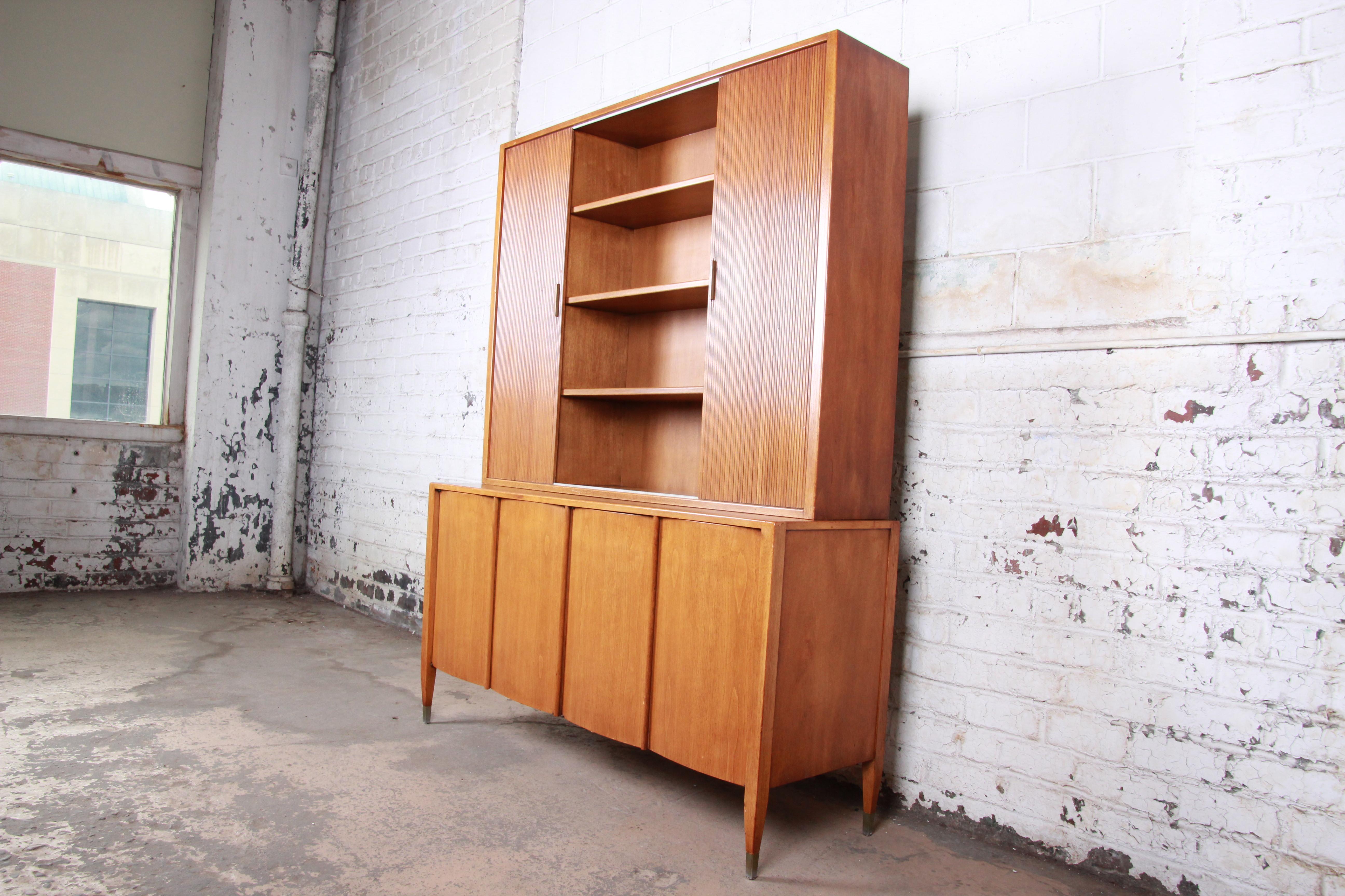A gorgeous Mid-Century Modern sideboard credenza with bookcase hutch top by Sligh Furniture of Grand Rapids. The credenza features beautiful walnut wood grain with sleek midcentury lines. The top has three shelved cabinets with two sliding wood