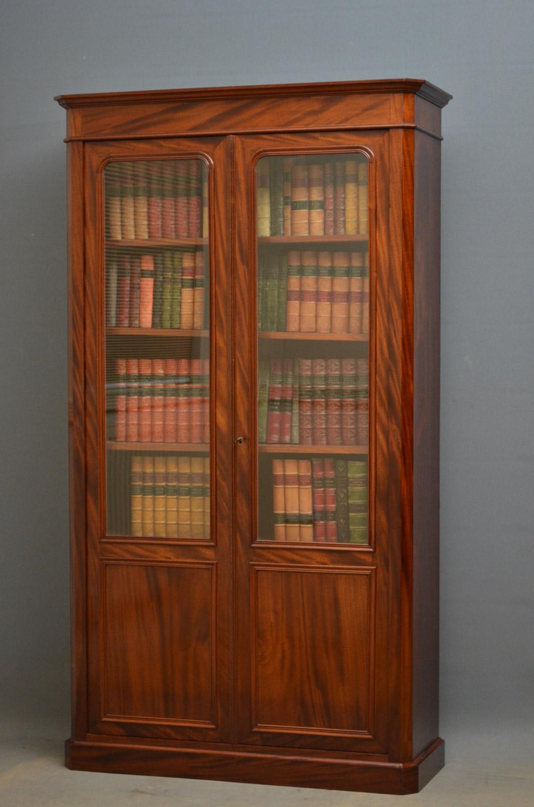 Sn4381, 19th century French, mahogany bookcase of simple and elegant form, having molded cornice and a pair of glazed and paneled doors fitted with original working lock and a key, enclosing 4 height adjustable shelves, all standing on plinth base.