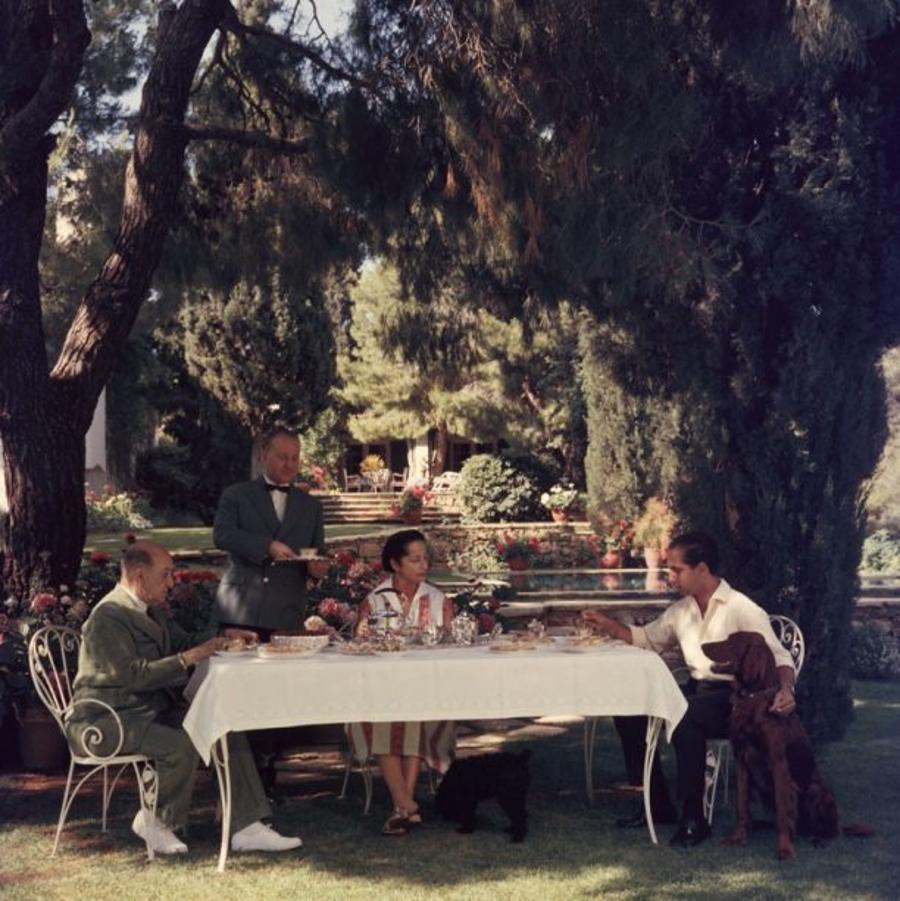 Al Fresco Tea 
1961
by Slim Aarons

Slim Aarons Limited Estate Edition

Colonel Dimitris Levidis enjoying a meal in the fresh air at Harvati with his wife and son, July 1961

unframed
c type print
printed 2023
20 x 20"  - paper size


Limited to 150