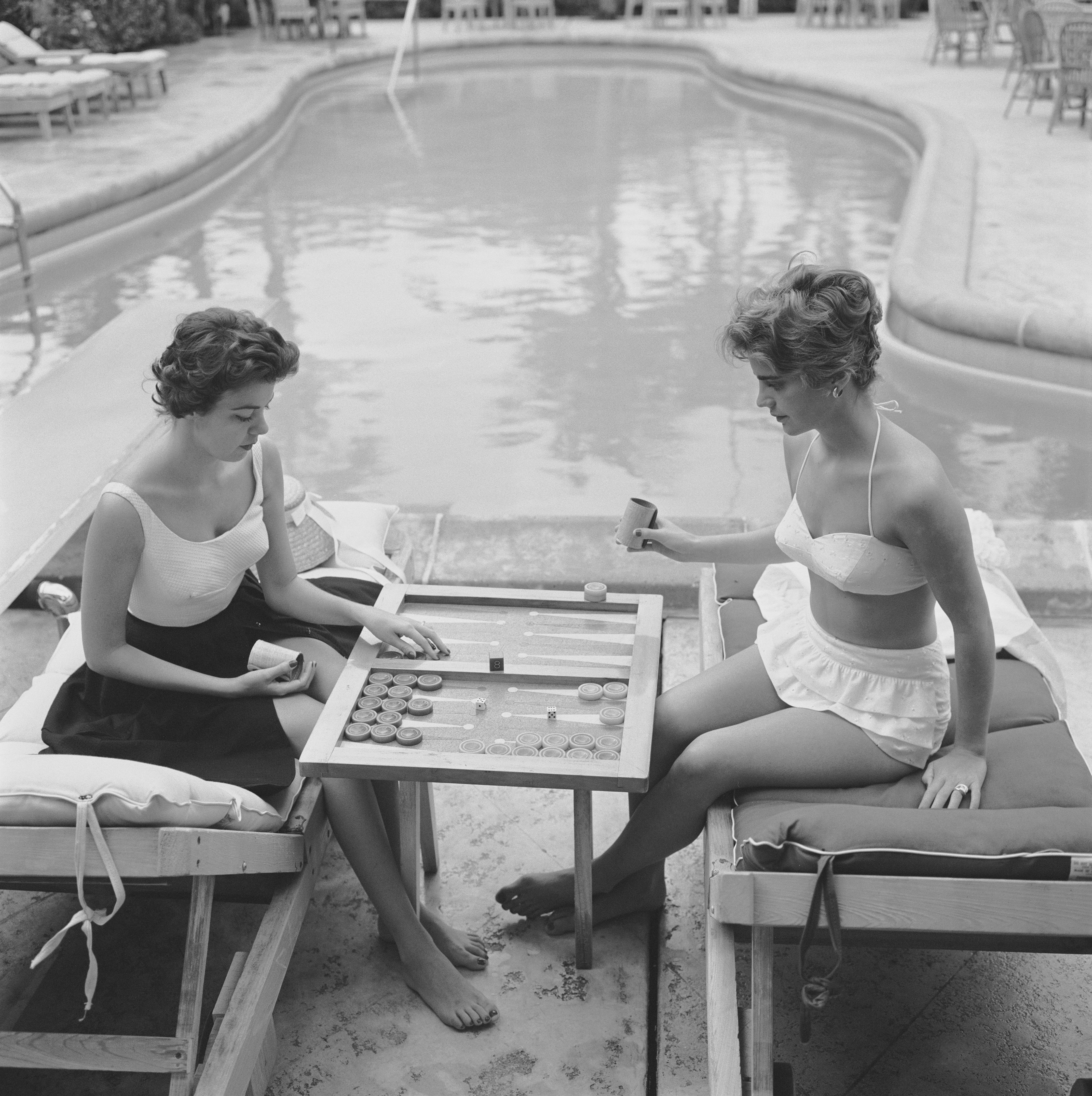 Countess Peter Jean-Baptiste de Manio (left) and Mary-Beth Turner playing backgammon by a swimming pool in Palm Beach, Florida, 1959.

Once a year, we uncover never-before-seen Slim Aarons images! This is one of fifteen from our new collection. A