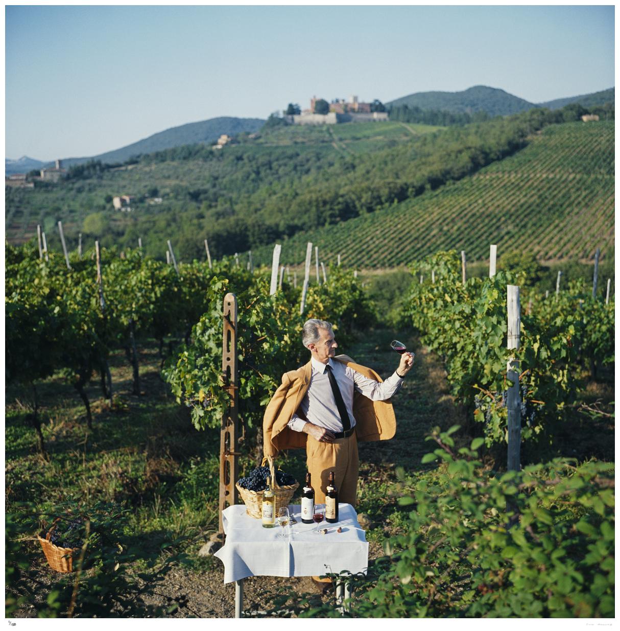 Barone Bettino Ricasoli 1983 - Slim Aarons 

El vinicultor Barone Bettino Ricasoli posa sosteniendo una copa de vino junto a una mesa en la que hay tres botellas de vino y una cesta de uvas, en un viñedo de Siena, Italia, 1983.

41 x 41 cm Tamaño
