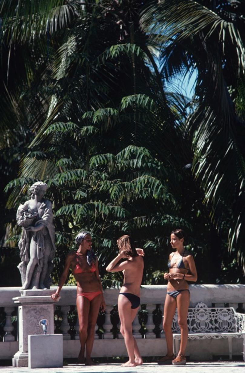 Bikinis In Haiti 
1975
by Slim Aarons

Slim Aarons Limited Estate Edition

Marni Morrell and Denise Schluscer with a third woman, all wearing bikinis, pose beside a statue on a bridge in Haiti, in January 1975

unframed
c type print
printed 2023
20