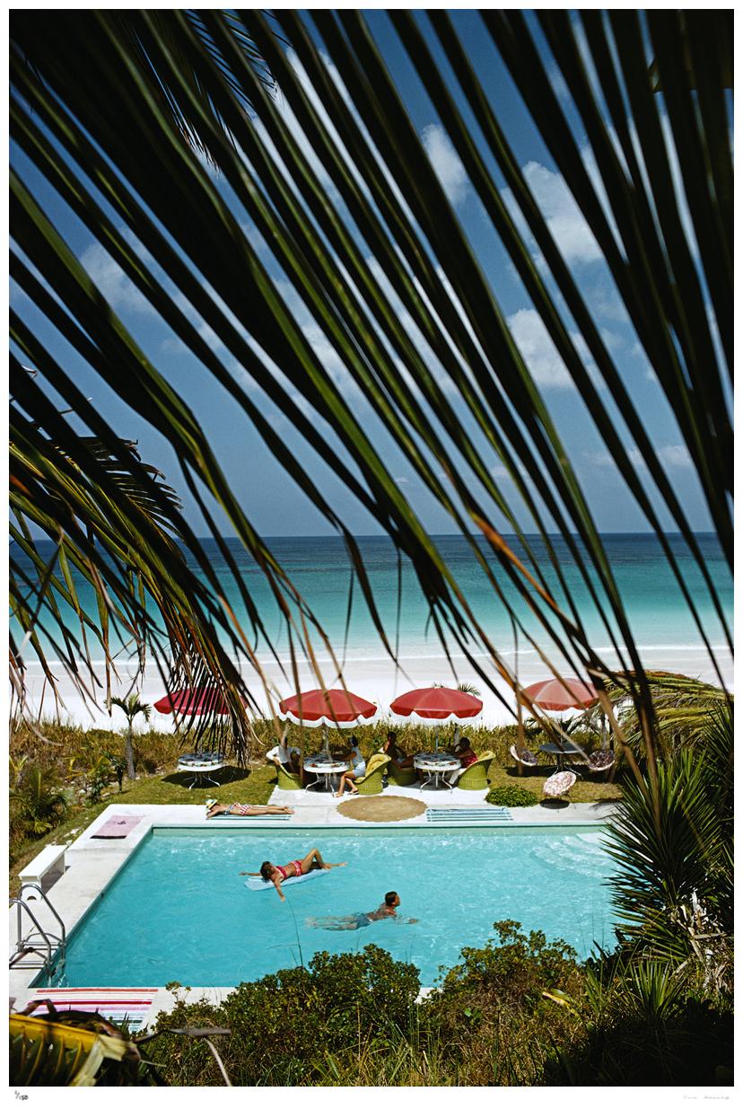 Bliss Bahamas 1967 - Slim Aarons 

Una piscina, vista attraverso le fronde di una palma, con due persone che nuotano e un gruppo di persone sedute ai tavoli a bordo piscina alle Bahamas, maggio 1967

30 x 20" pollici / 61 x 51 cm formato carta