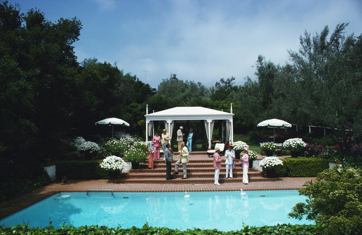 'California Garden Party'  Limited Slim Aarons Estate Edition

	
Guests attend a poolside luncheon at the home of Dorothy Laughlin in Santa Barbara, California, May 1975. 

Typically 'Slim' this photograph epitomises elegant travel and the vintage