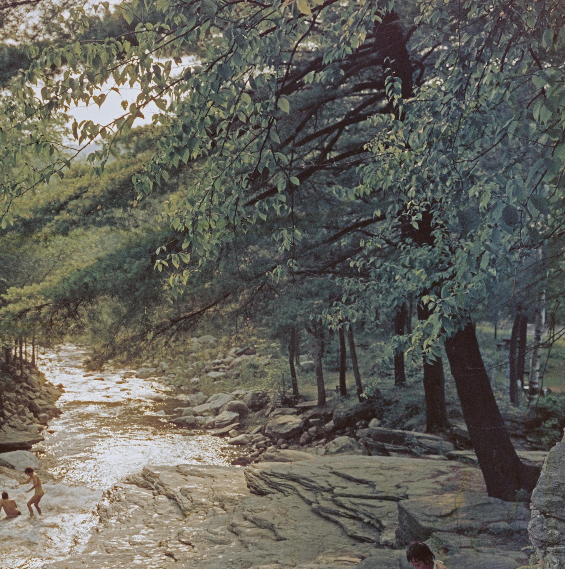 Dieses Landschaftsfoto aus den späten 1960er Jahren, aufgenommen vom Society-Fotografen Slim Aarons, zeigt eine Familie, die am Ufer des Whiting River in der Nähe von Campbell Falls, Massachusetts, USA, 1959, ein Picknick macht.

Dies ist eine