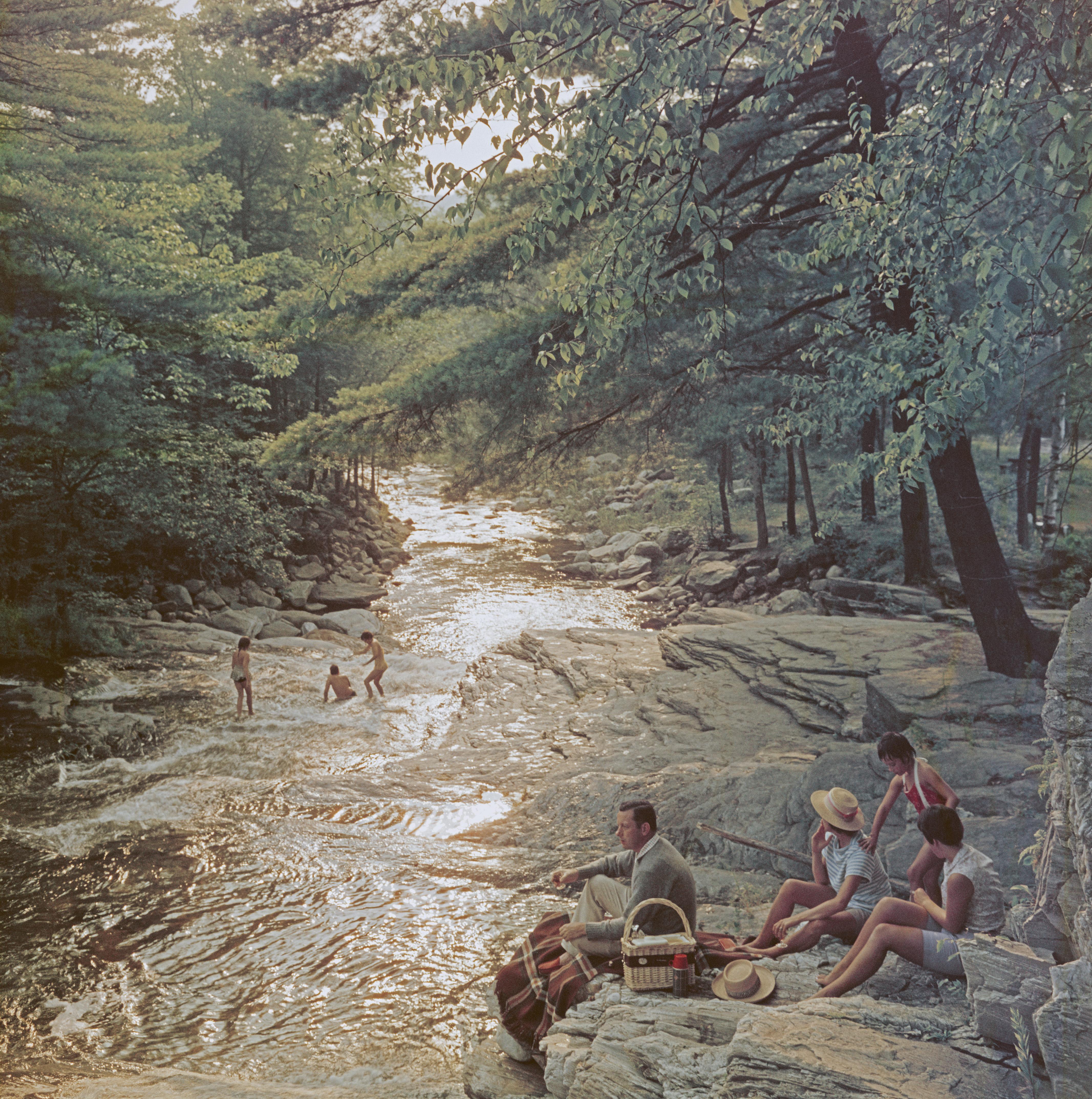 A family enjoying a picnic on the bank of the Whiting River near Campbell Falls, Massachusetts, USA, 1959. 

Once a year, we uncover never-before-seen Slim Aarons images! This is one of fifteen from our new collection. A word from our Curator Shawn