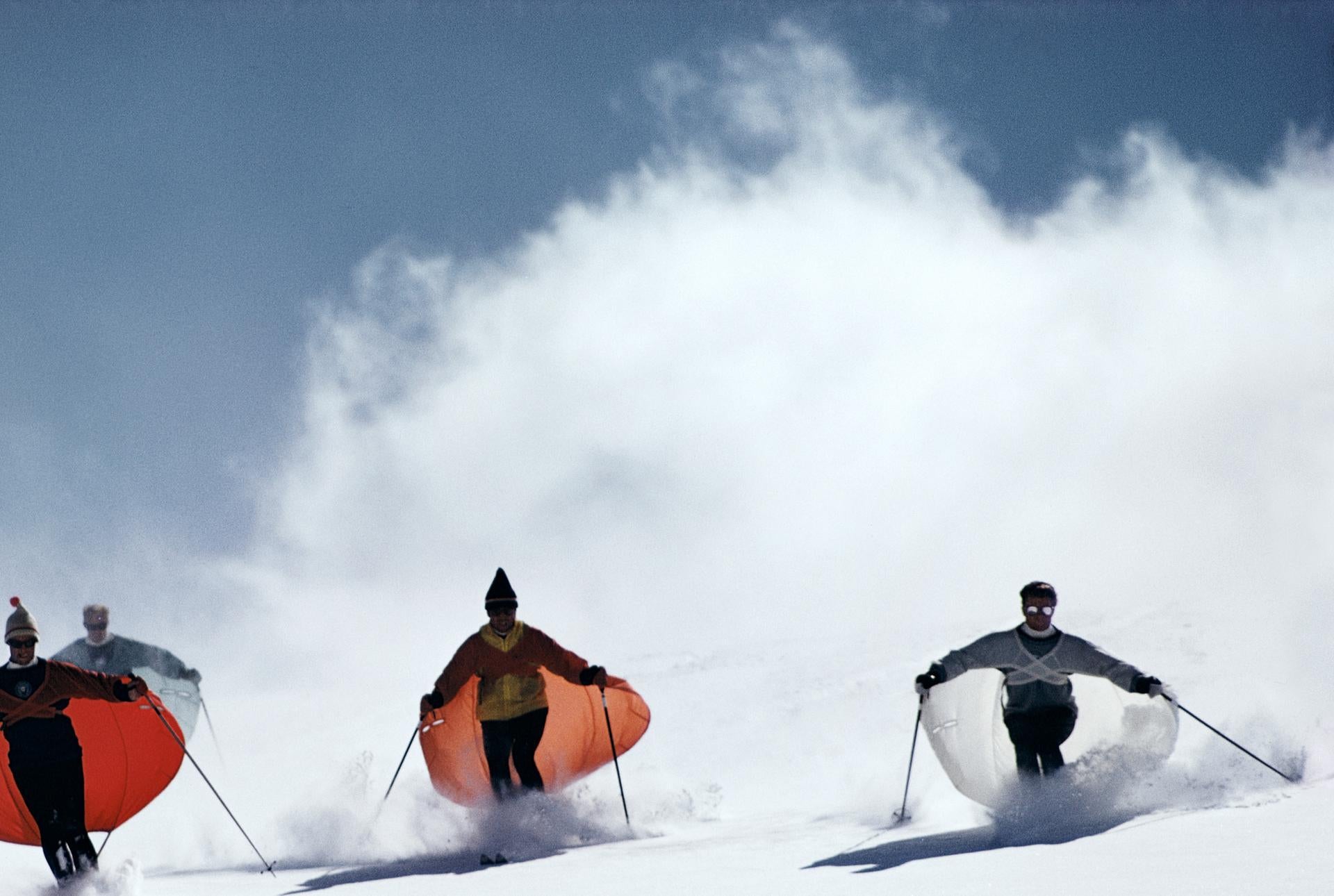 Caped Skiers, Colorado, Nachlassausgabe, Landschaftsfotografie

Dieses Landschaftsfoto aus den späten 1960er Jahren, aufgenommen vom Society-Fotografen Slim Aarons, zeigt den Skimaster Stein Eriksen, der die Skifahrer in Snowmass-at-Aspen, Colorado,