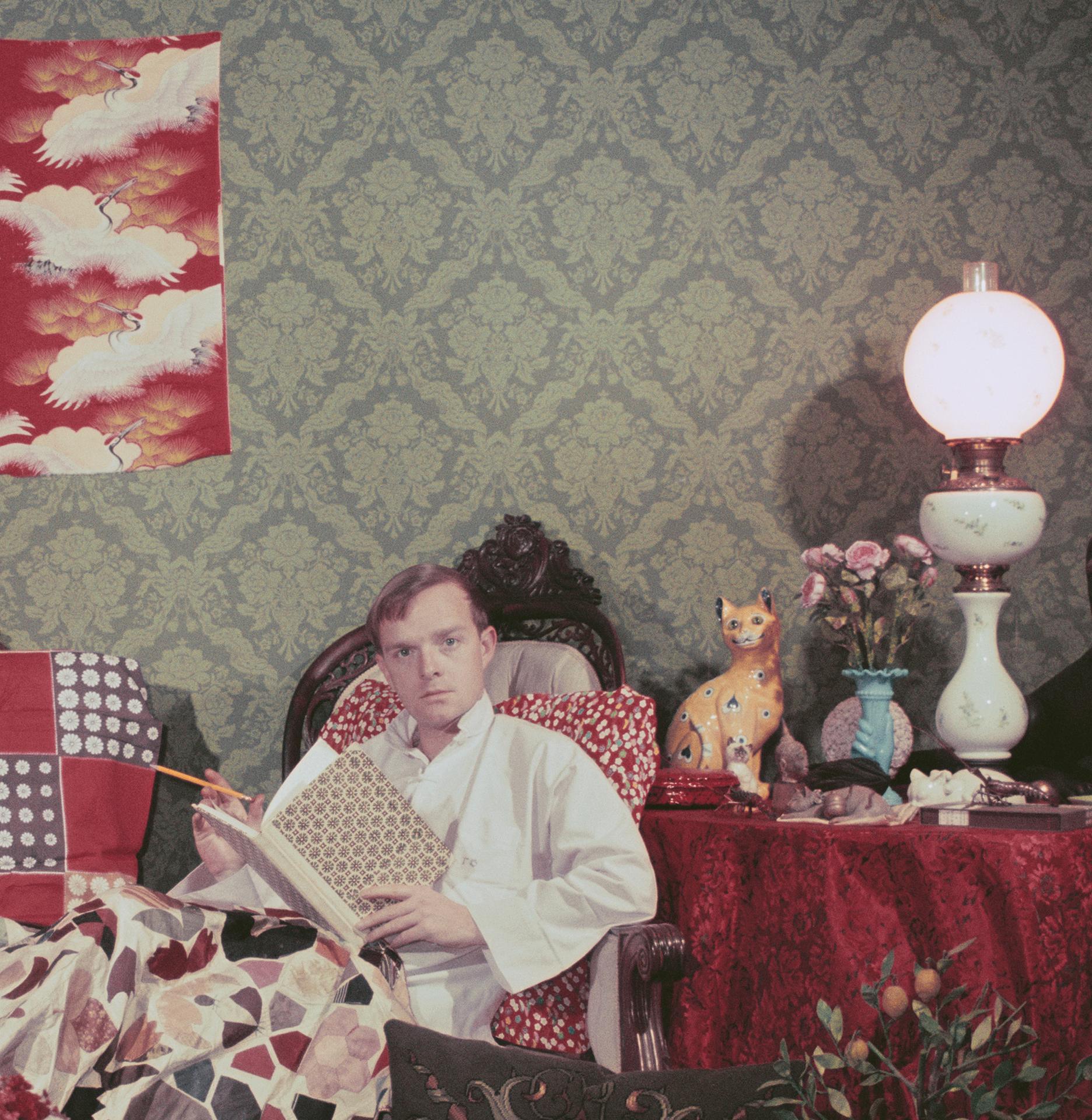 Dieses Porträtfoto des Society-Fotografen Slim Aarons aus den späten 1950er Jahren zeigt den Schriftsteller Truman Capote (1924-1984), der sich mit einem Buch und einer Zigarette in seiner unaufgeräumten Wohnung in Brooklyn Heights, New York,