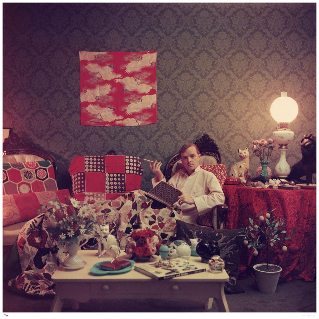 Capote At Home' by Slim Aarons

Author Truman Capote (1924 – 1984) relaxes with a book and a cigarette in his cluttered apartment, Brooklyn Heights, New York, 1958.

The renowned author is photographed in his fashionably and colourfully eclectic