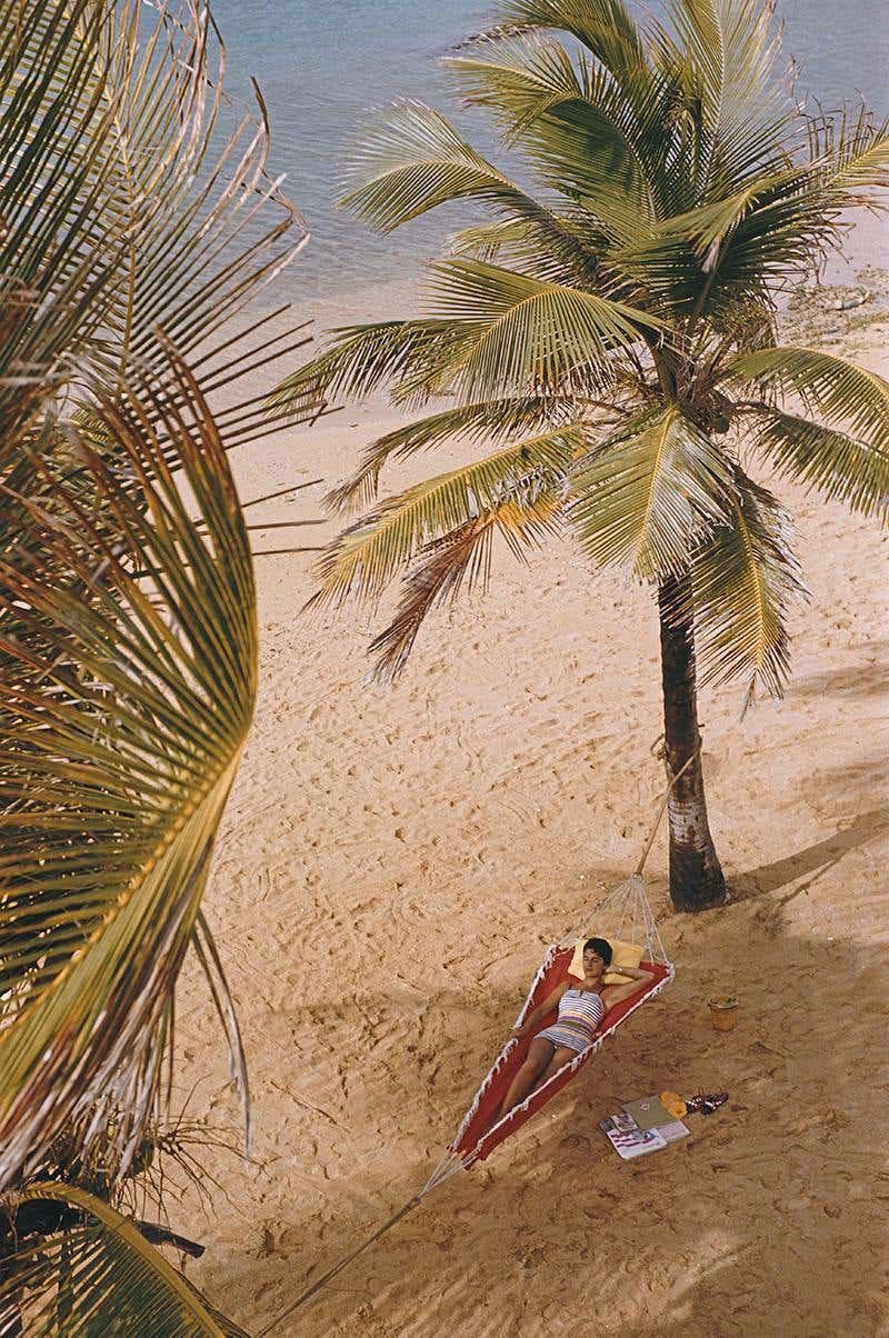 Caribe Hilton Strand
1956 (später gedruckt)
Chromogener Lambda-Druck
Nachlassauflage von 150 Stück

Eine Frau liegt in einer Hängematte, die zwischen Palmen am Strand des Caribe Hilton in San Juan, Puerto Rico, aufgehängt ist, März 1956.