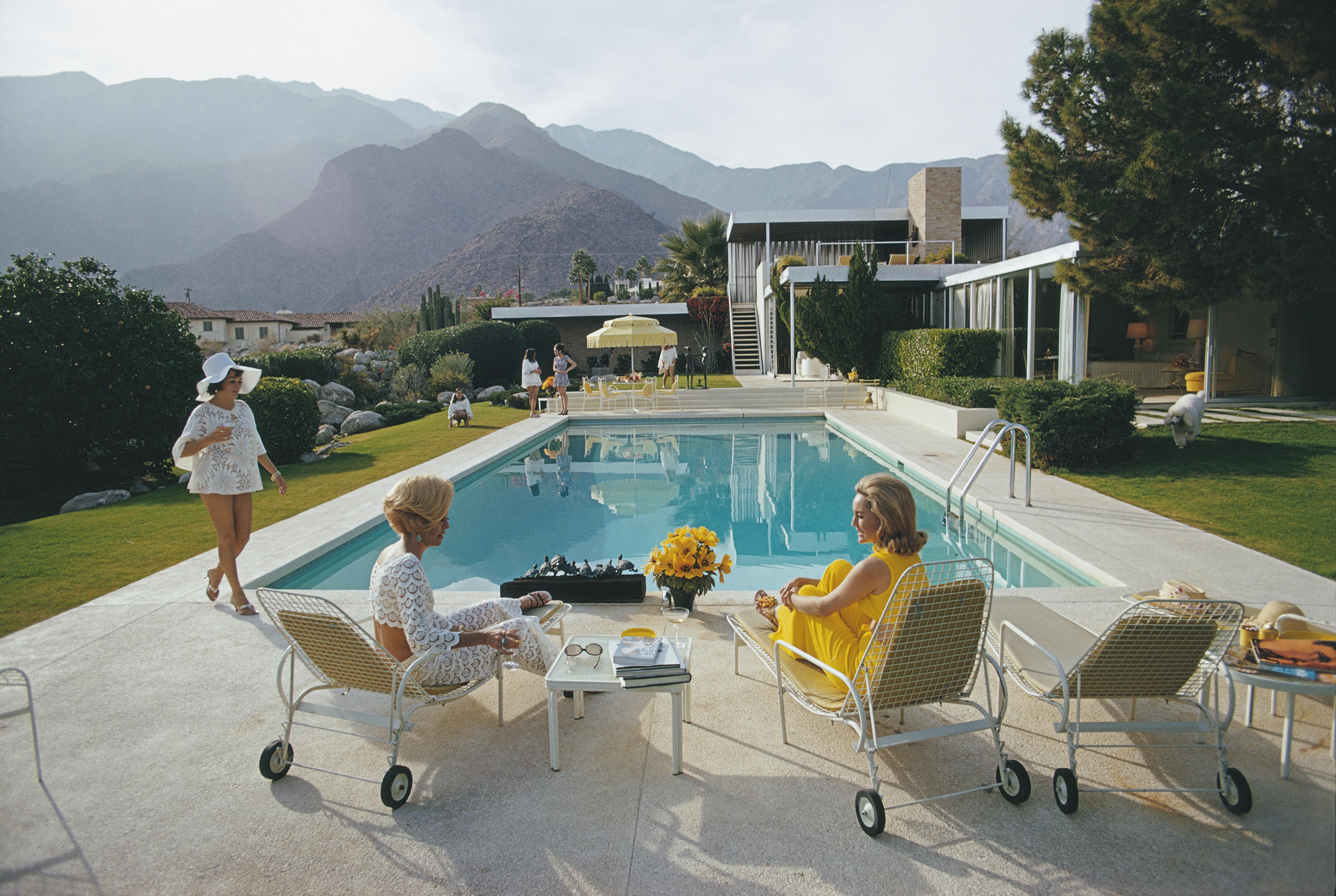 'Catch Up by the Pool' 1970 Slim Aarons Limited Estate Edition Print 

Former fashion model Helen Dzo Dzo Kaptur (in white lace), Nelda Linsk (in yellow), wife of art dealer Joseph Linsk, and actress Lita Baron (in white sunhat) at the Kaufmann