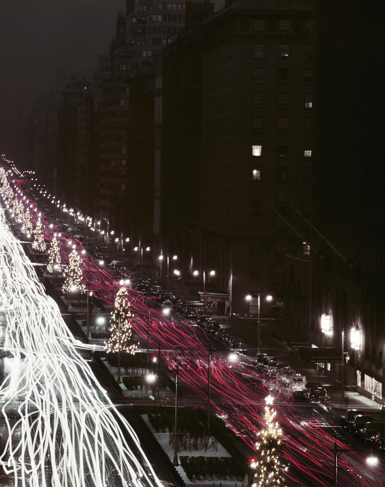 Cette photographie de paysage urbain du début des années 1950, prise par le photographe mondain Slim Aarons, montre des arbres de Noël et des traînées lumineuses rouges et blanches de voitures sur Park Avenue, à New York, à la période de Noël.

Il