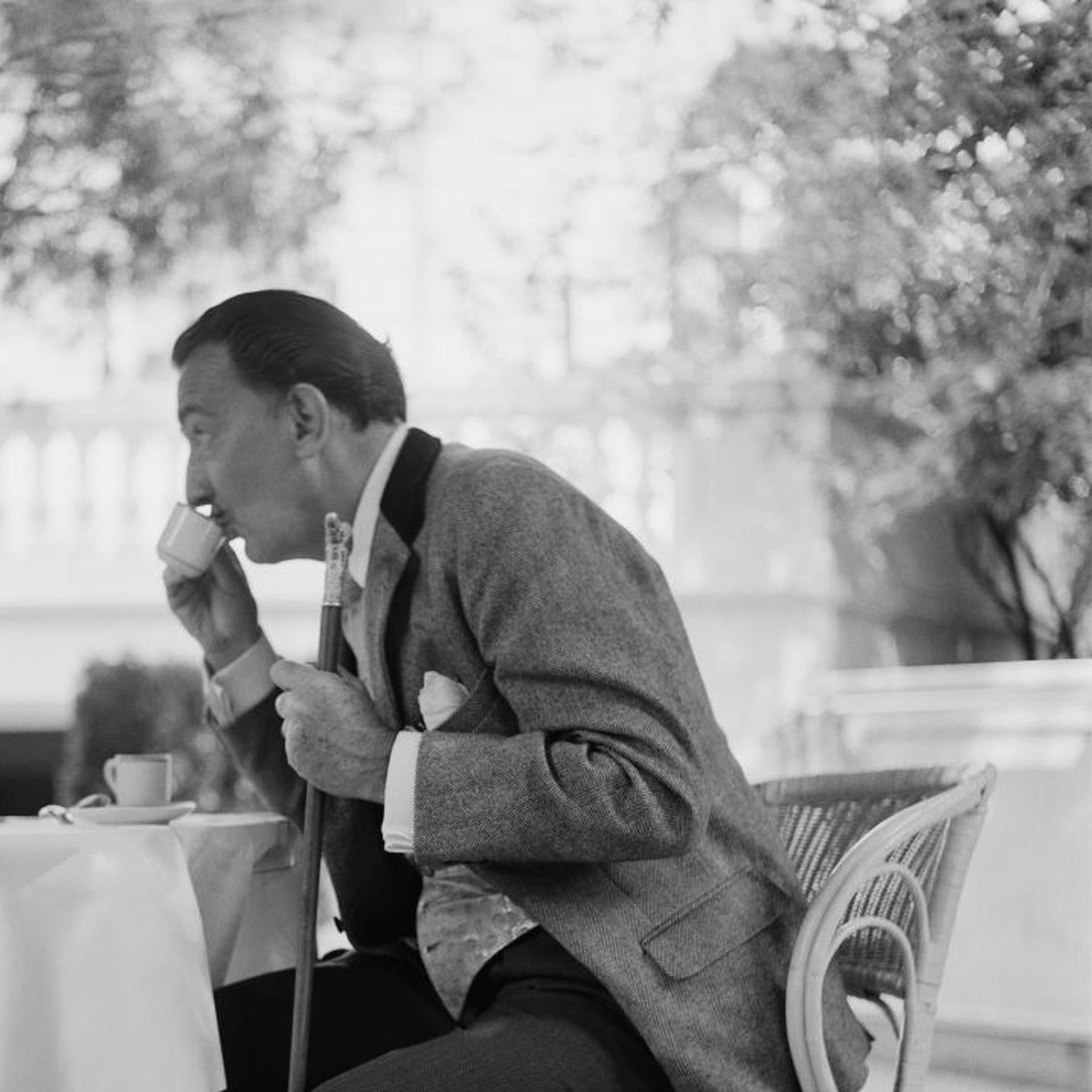 This mid-1950s portrait photograph, captured by society photographer Slim Aarons, features Spanish artist Salvador Dali enjoys a cup of coffee on the terrace of the Ritz Hotel, Madrid.

This is an estate stamped and hand numbered edition of 150 with