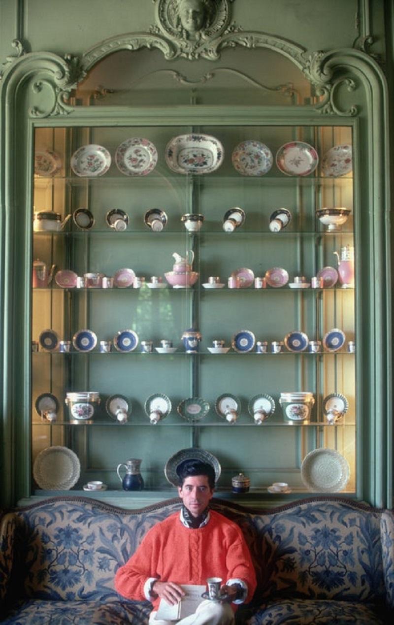 comte d'Arcangues 1986 Slim Aarons Edition Limitée 

1986, Michel, Comte d'Arcangues, contre un mur de porcelaines de Sèvres et de la Compagnie des Indes à son château d'Arcangues, Biarritz, France. 

Produit à partir de la transparence