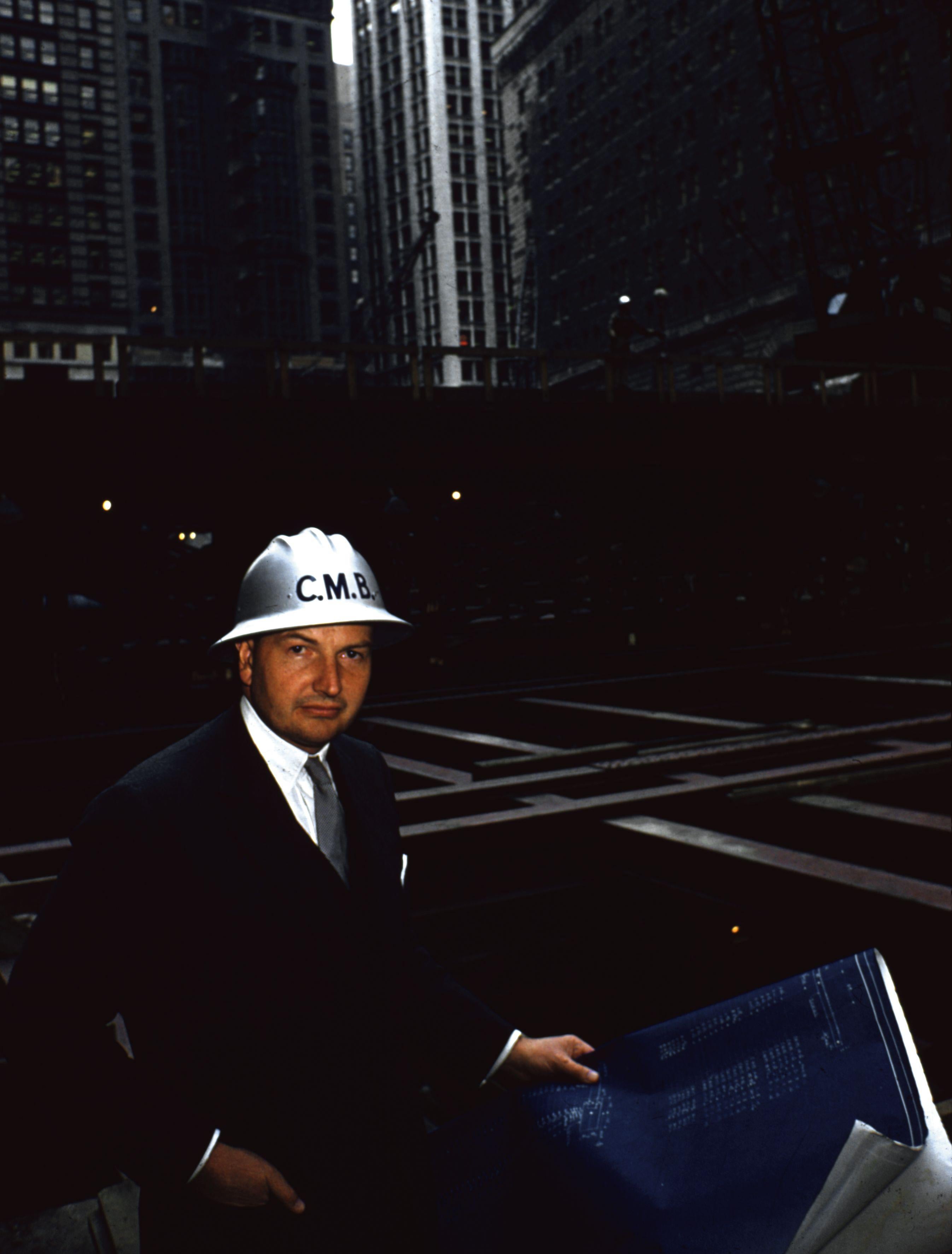 'Financial Planning ?' 1965 Slim Aarons Limited Estate Edition Print 

circa 1965: Financier David Rockefeller wears a hard hat as he stands surrounded by girders in the excavation for the Chase Manhattan Plaza in the Wall Street area of New York.