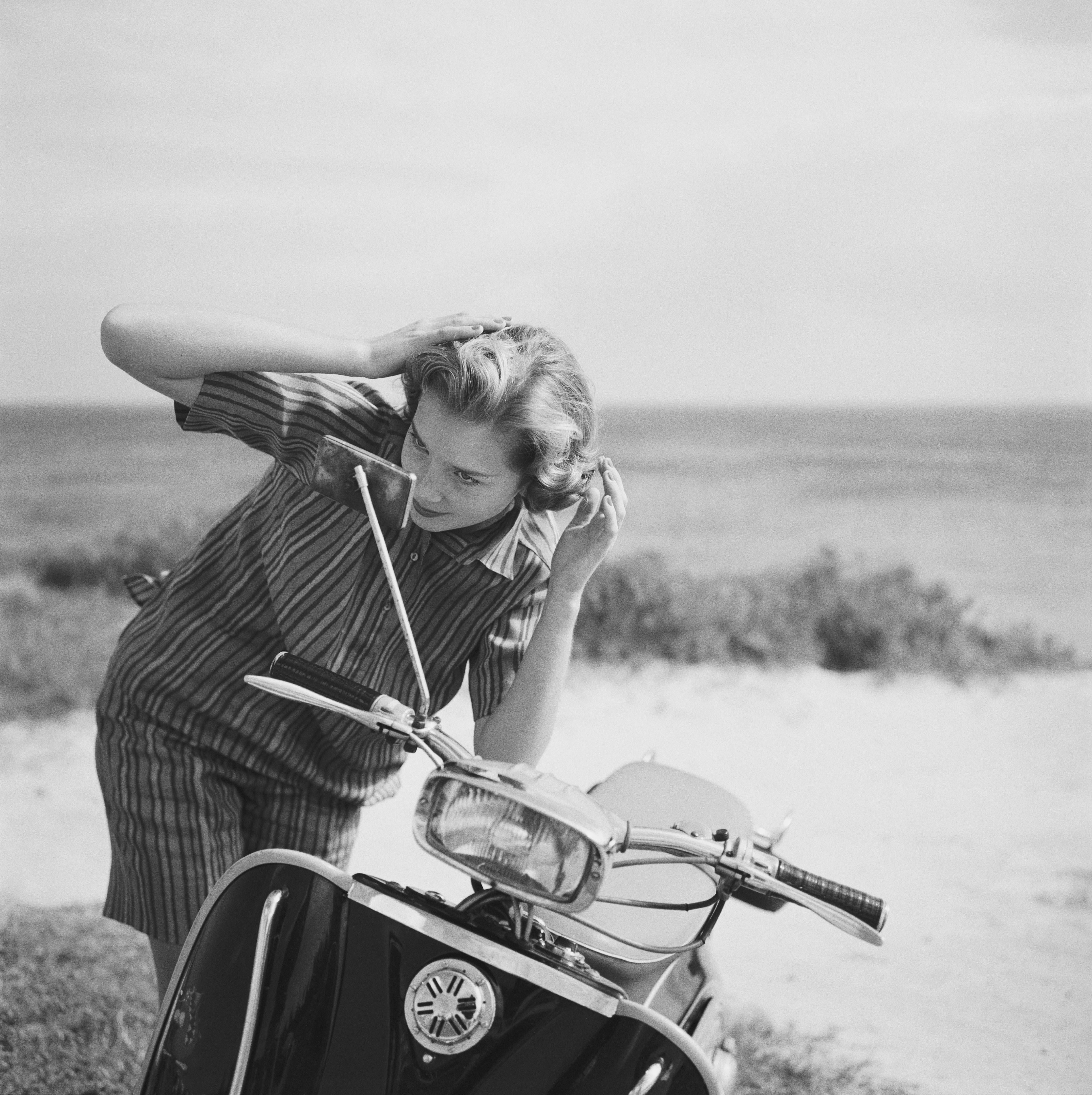 Faith Gibbons checks her hair in the mirror of a motor scooter, Bermuda, 1958. She is wearing a striped Irish linen overblouse by Donald Davies of Dublin.

Once a year, we uncover never-before-seen Slim Aarons images! This is one of fifteen from our