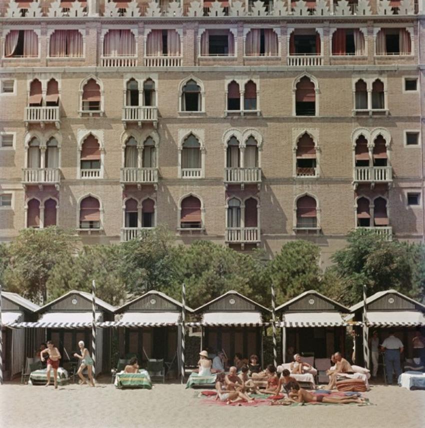 Hotel Excelsior 
1957
by Slim Aarons

Slim Aarons Limited Estate Edition

The beach front of the luxurious Excelsior Hotel on the Venice Lido, 1957. 



unframed
c type print
printed 2023
16×16 inches - paper size


Limited to 150 prints only –