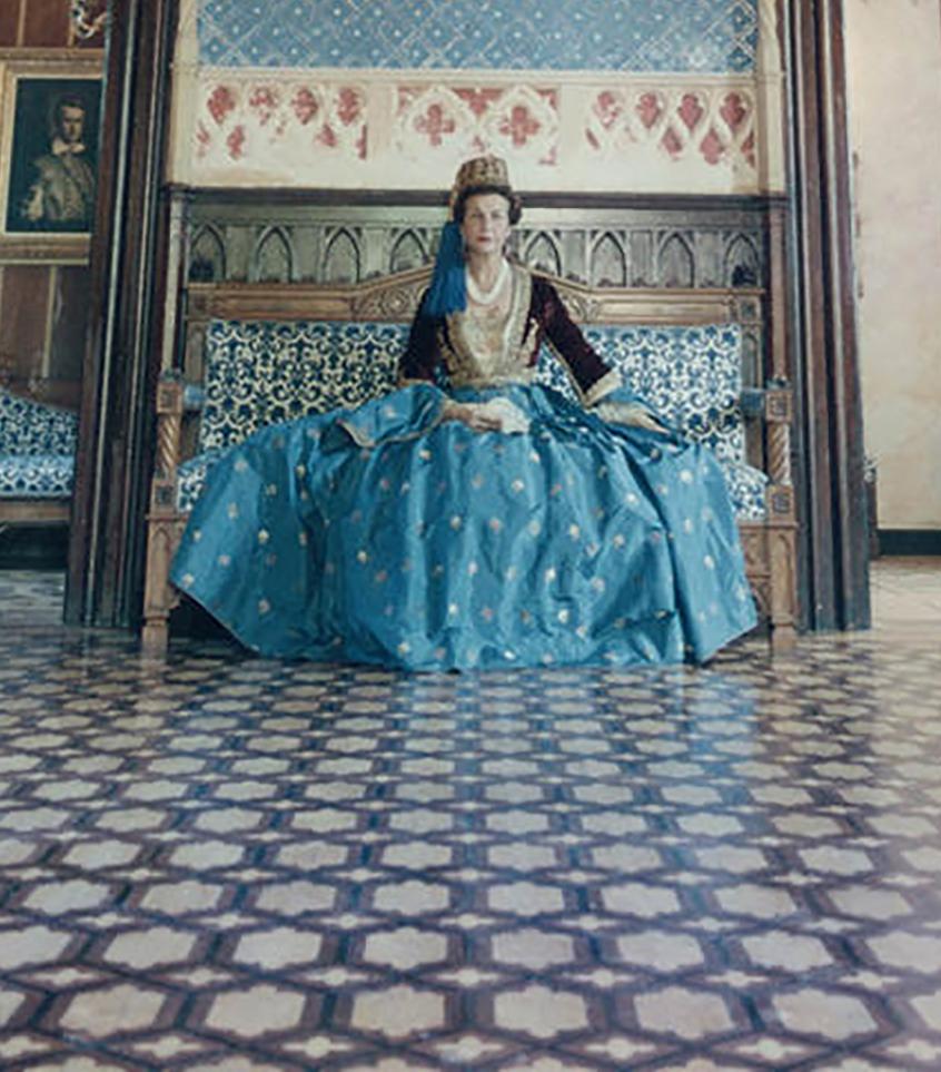 Décembre 1961 - Madame Jean Serpieri est assise dans la salle de bal de la Tour La Reine près d'Athènes, portant une robe ayant appartenu à l'épouse d'Othon, le premier roi de la Grèce moderne. Le palais appartenait également à l'origine au roi Otto