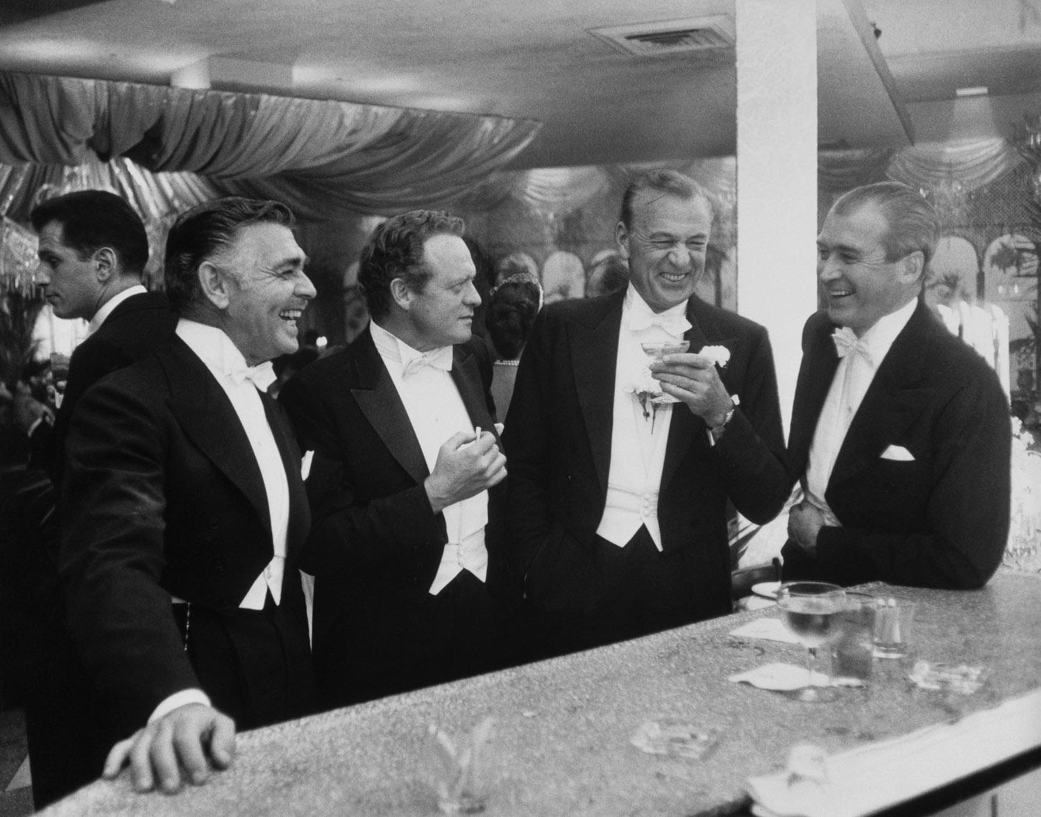Les rois d'Hollywood 1957 
Slim Aarons Limited Estate Edition 

Clark Gable (1901 - 1960), Van Heflin (1910 - 1971), Gary Cooper (1901 - 1961) et James Stewart (1908 - 1997) 
s'amusant d'une plaisanterie lors d'une fête du Nouvel An organisée chez
