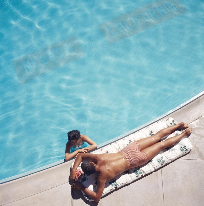 Pareja del Lago Tahoe 

Una pareja se relaja en una piscina bajo el sol del verano cerca del lago Tahoe, California, 1959. La línea del fondo de la piscina marca la frontera estatal entre Nevada y California.

Esta fotografía, un clásico de Slim