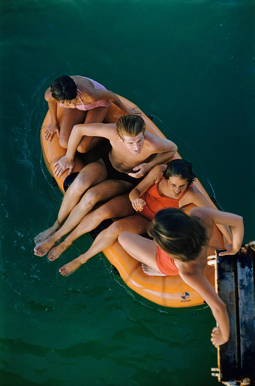 Lido Life: A group of friends squeeze onto an inflatable raft at the Venice Lido, Venice, Italy, 1957.

This vibrant photograph by Slim Aarons, taken in 1957 at the Venice Lido, encapsulates the quintessential joy and carefree spirit of summertime