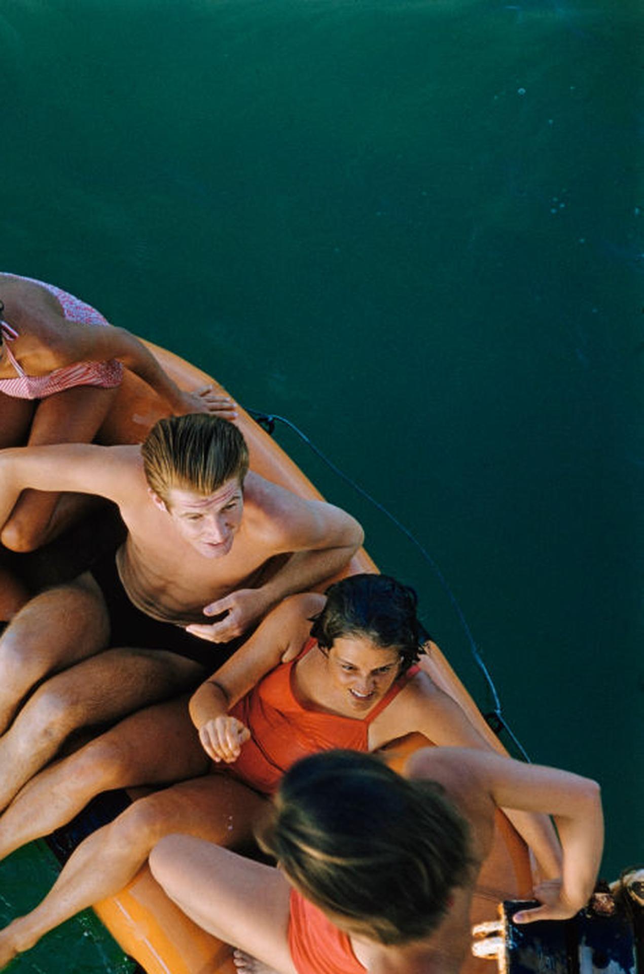 Questo ritratto della metà degli anni '50, scattato dal fotografo di società Slim Aarons, ritrae un gruppo di amici che si stringono su una zattera gonfiabile al Lido di Venezia, Venezia, Italia.

Si tratta di un'edizione stampata e numerata a mano