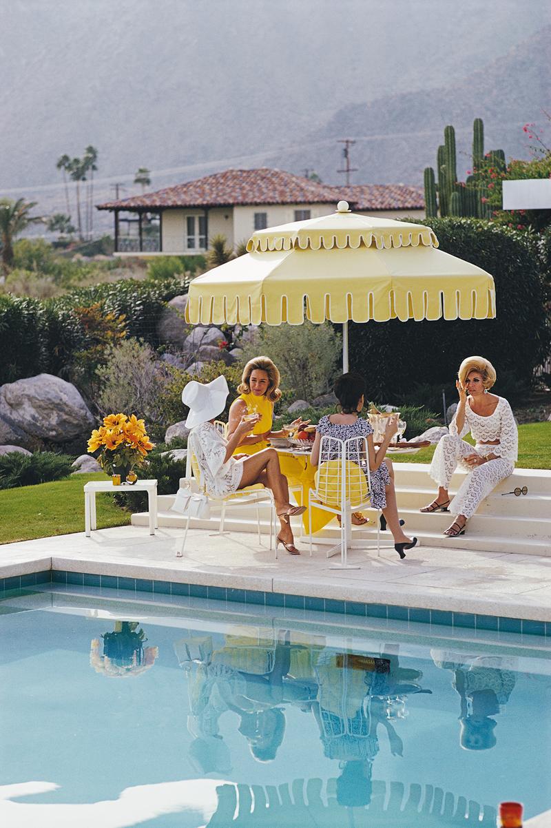 nelda et ses amis" 1970 Slim Aarons Edition limitée de succession 

Dames au bord de la piscine de la Kaufmann Desert House à Palm Springs, Californie, janvier 1970. De droite à gauche, l'ancien mannequin Helen Dzo Dzo Kaptur (en dentelle blanche),