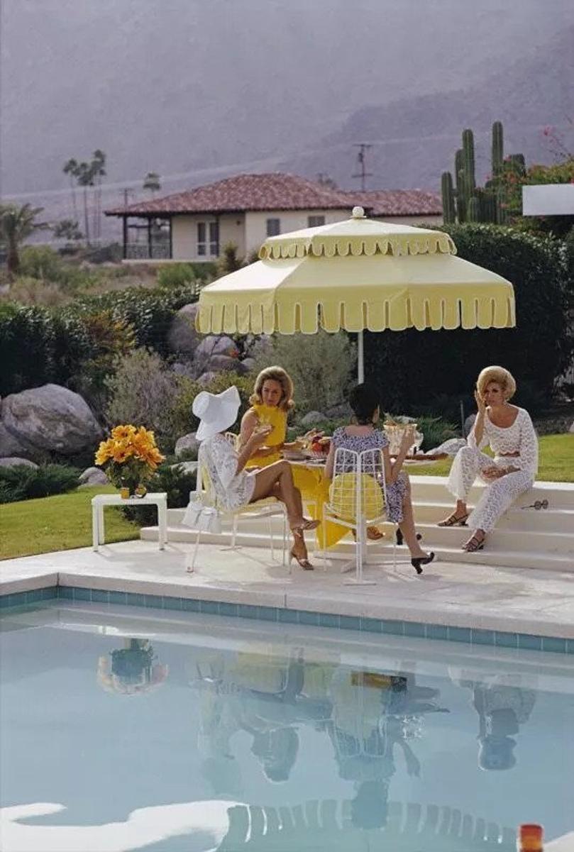 Nelda und Freunde 
1970
von Slim Aarons

Slim Aarons Limited Estate Edition

Damen am Pool des Kaufmann Desert House in Palm Springs, Kalifornien, Januar 1970. Von rechts nach links: das ehemalige Fotomodell Helen Dzo Dzo Kaptur (in weißer Spitze),